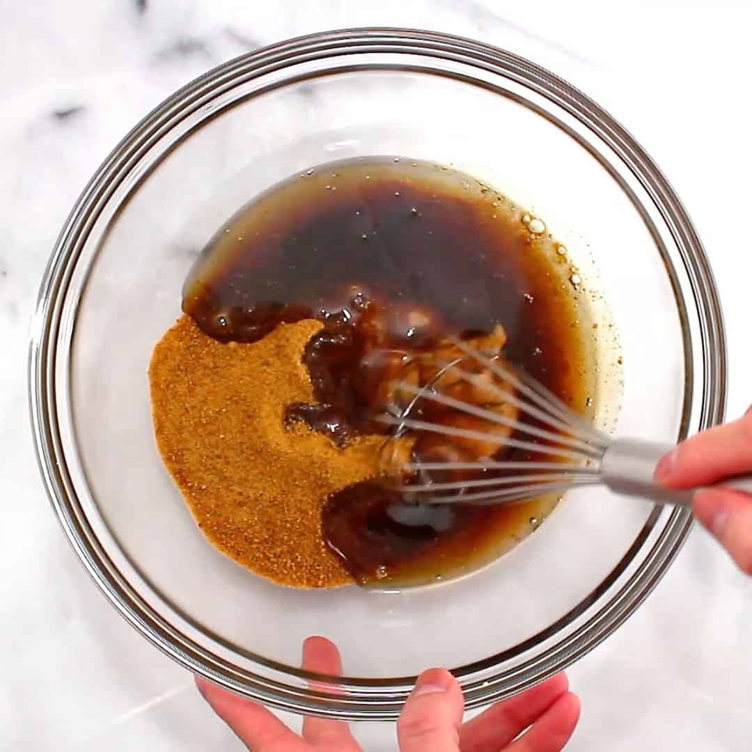 hand whisking wet ingredients for vegan brownies together in a glass bowl
