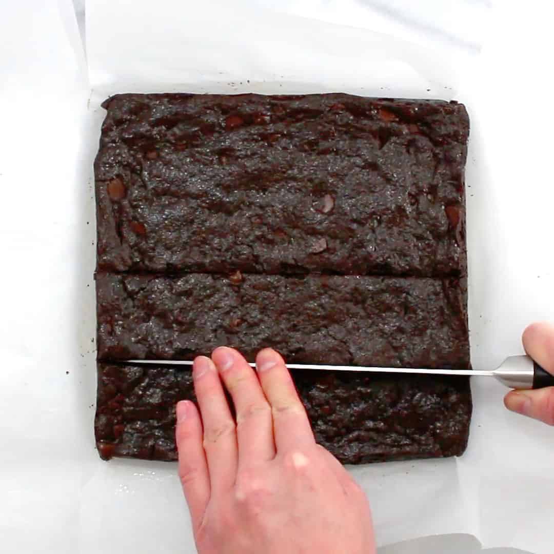 hand holding knife to slice fudgy vegan brownies into squares