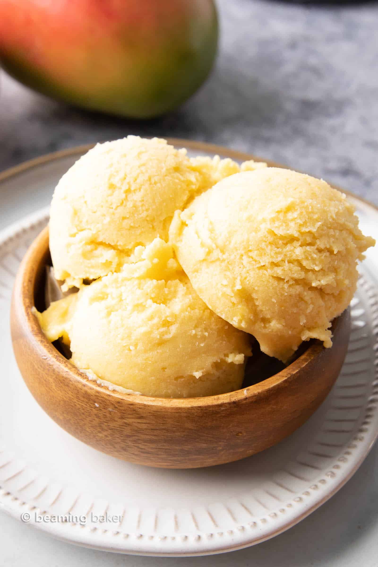 Closeup of bowl with three scoops of mango ice cream in it.