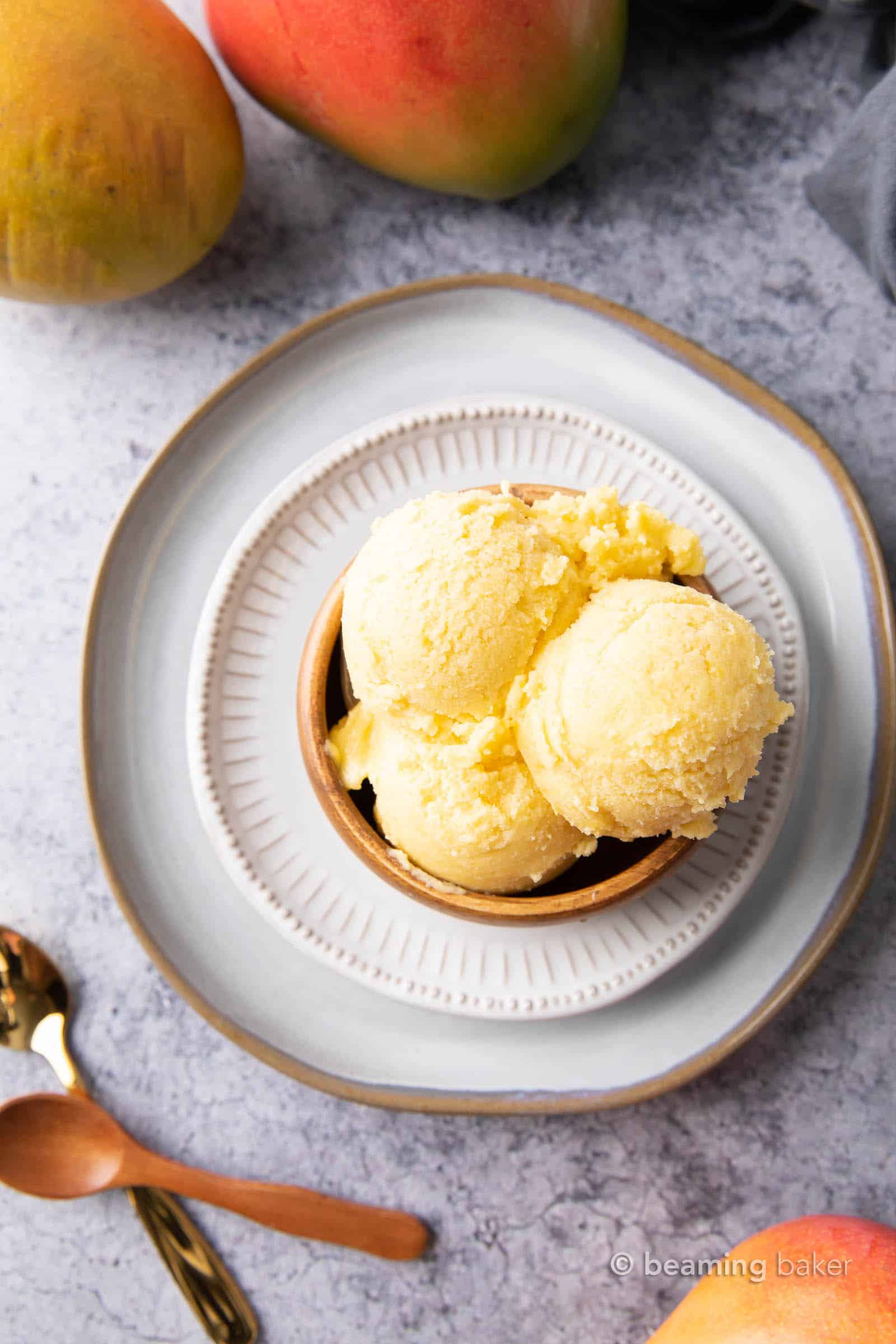 Overhead shot of bowl with mango coconut ice cream on top of serving plates.