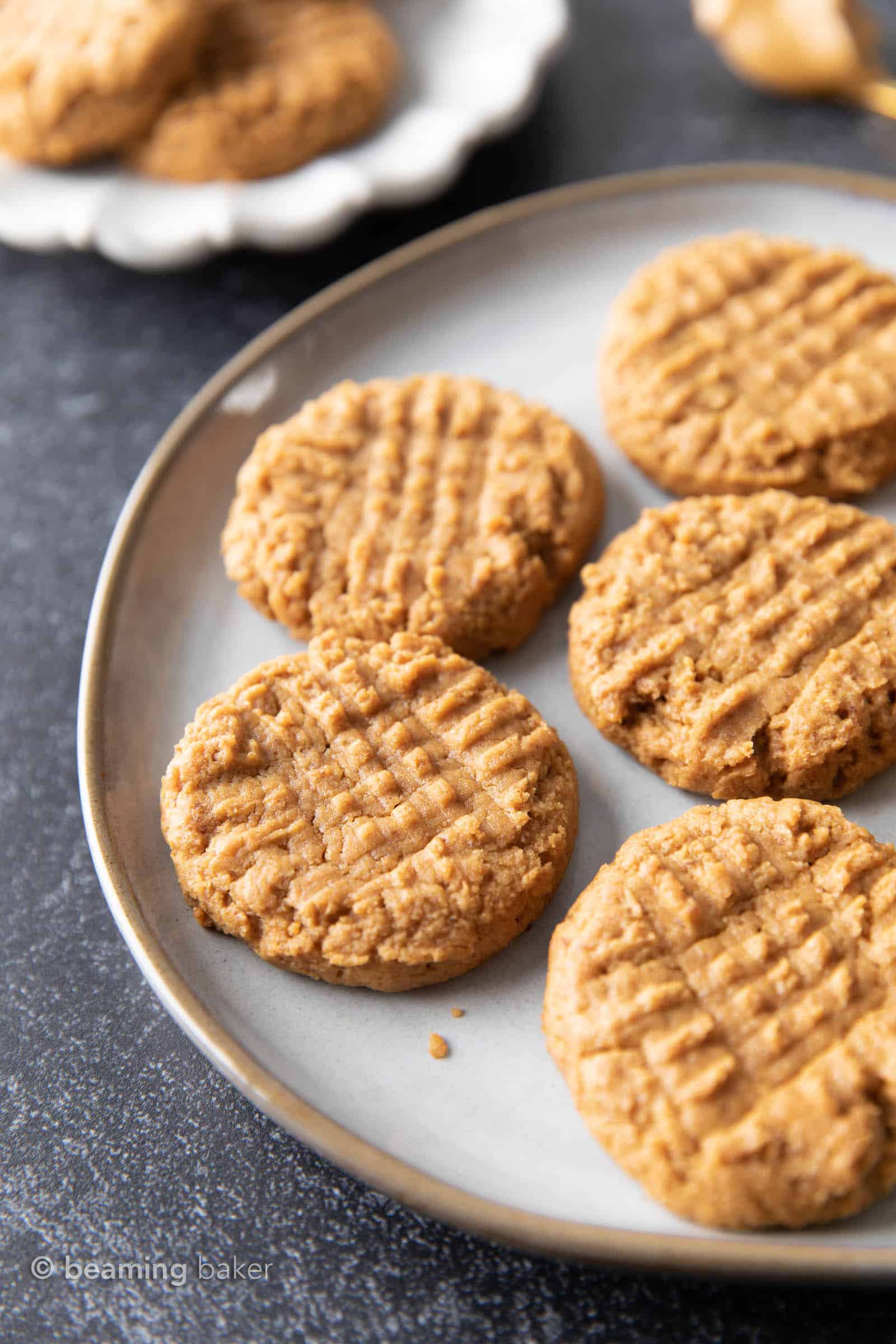 Peanut butter cookies spread out on a plate, sitting on a dark gray table.