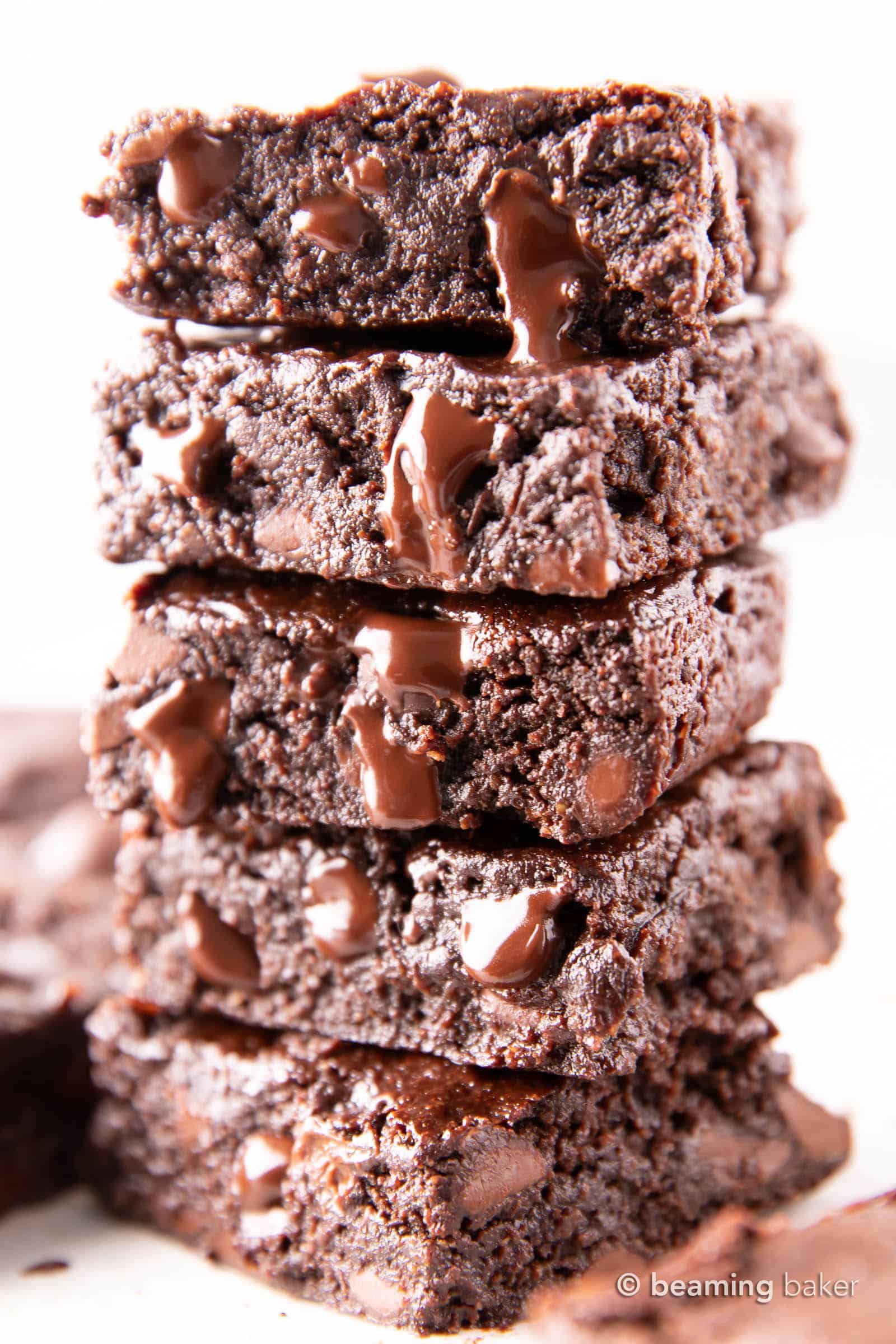 Stack of fudgy vegan brownies with chocolate chips melting down the side