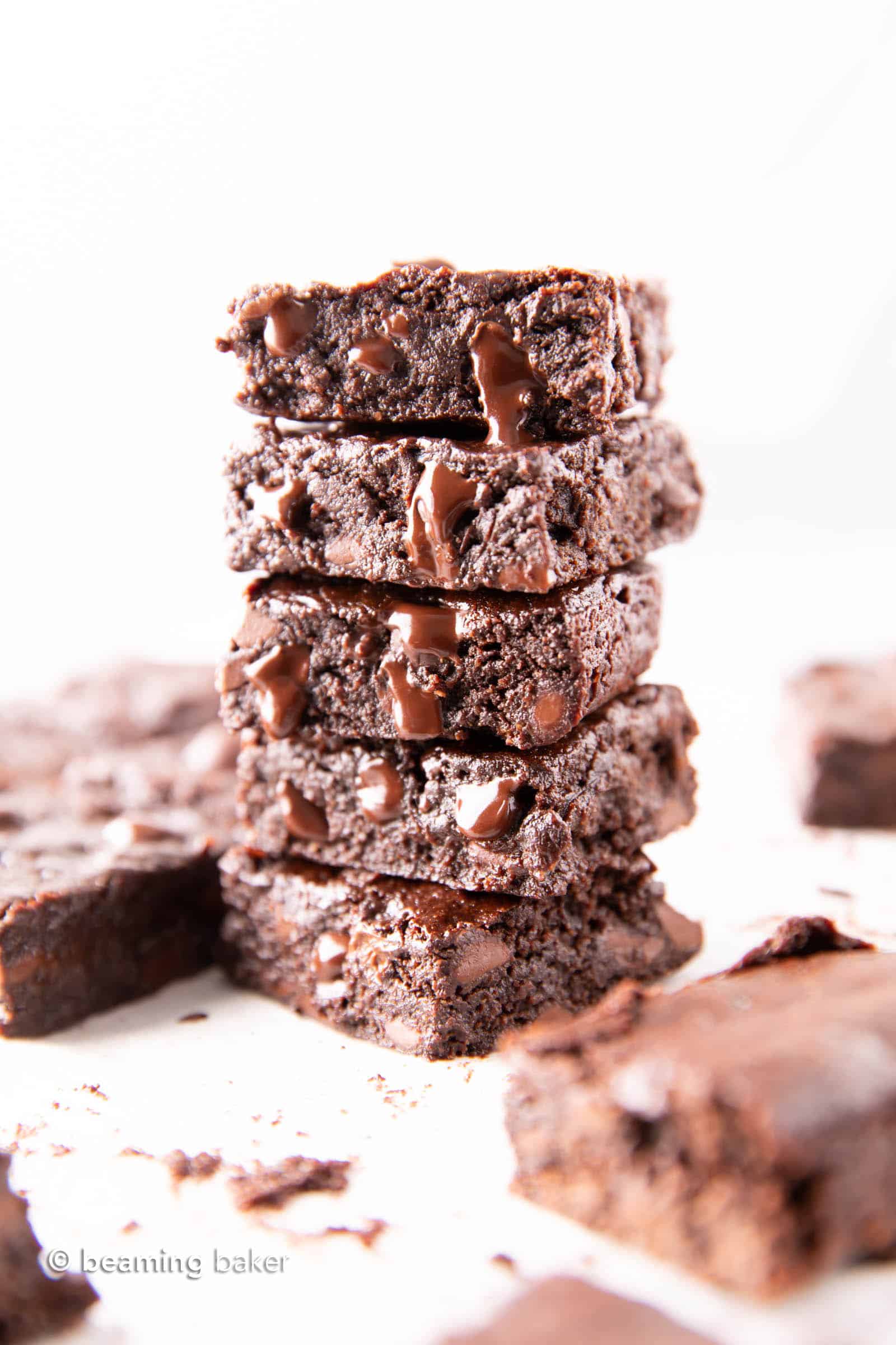 Tall stack of vegan brownies, with some brownies sitting on the table in the background