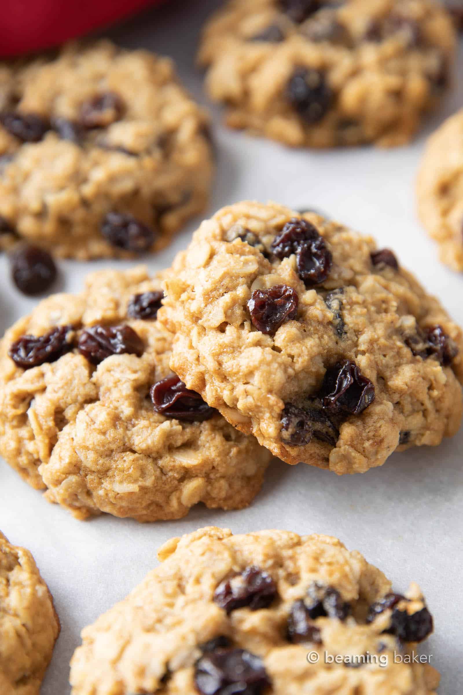 Two vegan gluten free oatmeal raisin cookies stacked on top of each other, with the top cookie leaning to the side