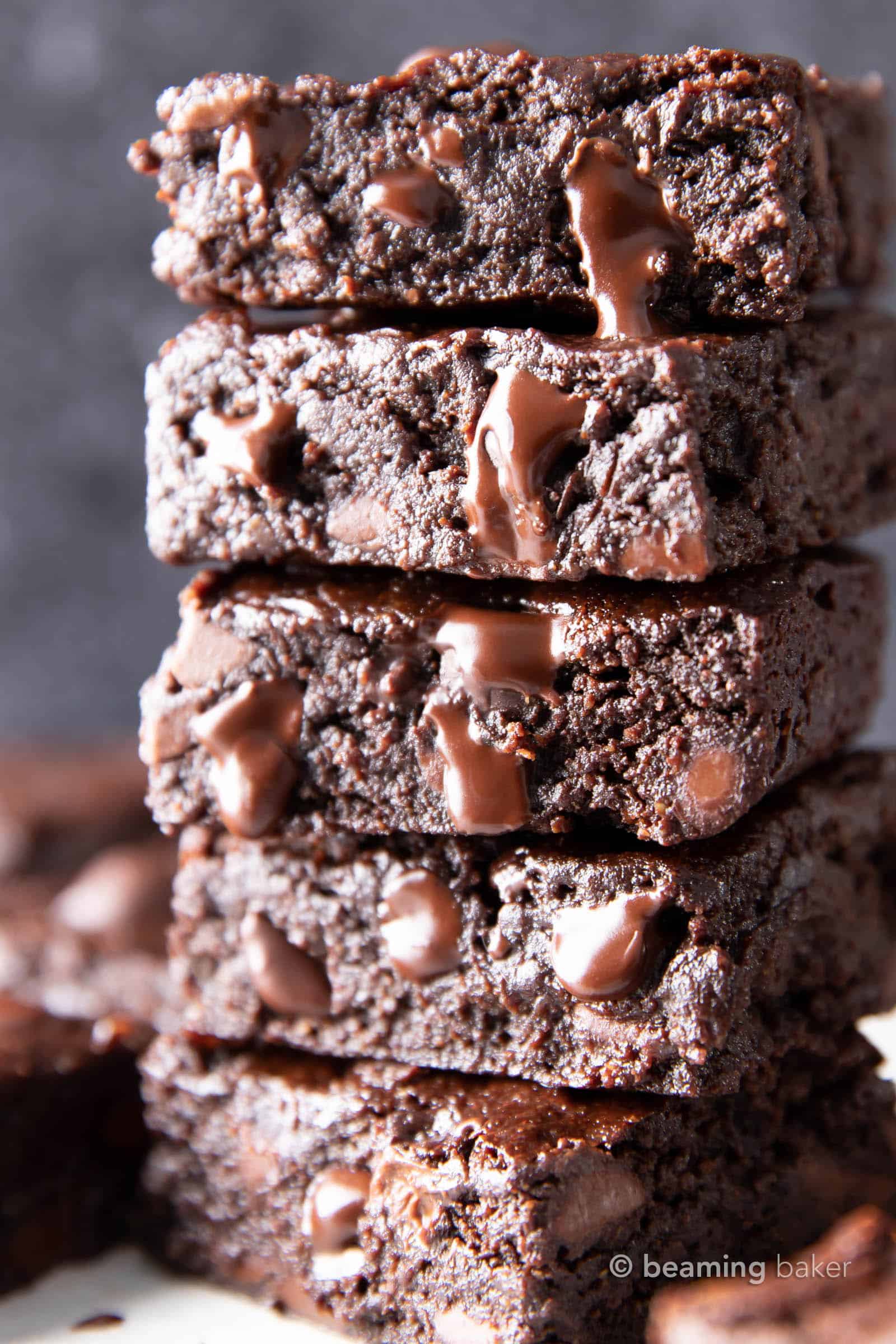 closeup stack of freshly baked vegan gluten free brownies with melty chocolate chips oozing out