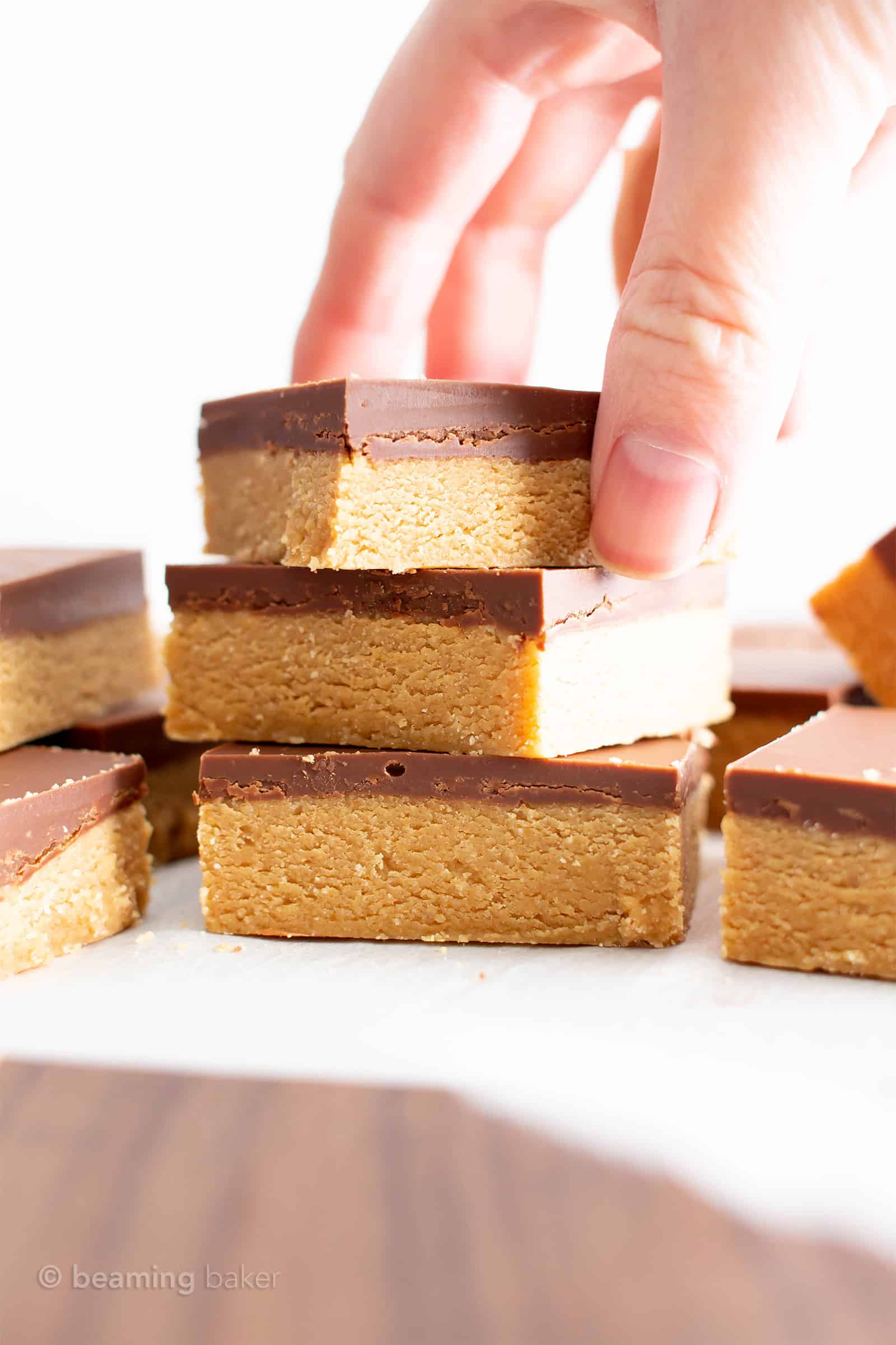 Stack of thee vegan gluten free peanut butter bars with a hand holding the top bar