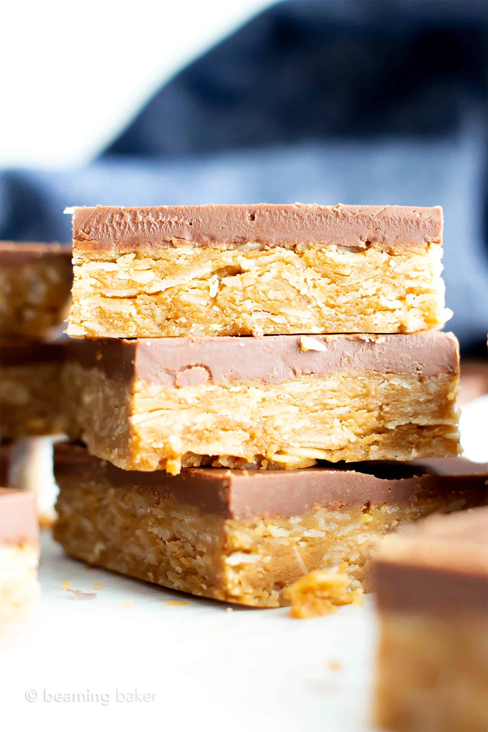 4 Ingredient Healthy No Bake Peanut Butter Cup Oat Bars: this vegan peanut butter oatmeal bars recipe is so easy to make & tastes like peanut butter cups! Chewy peanut butter oatmeal bars with a thick, chocolate topping. #Vegan #GlutenFree #Healthy #PeanutButter #Oats #Oatmeal | Recipe at BeamingBaker.com