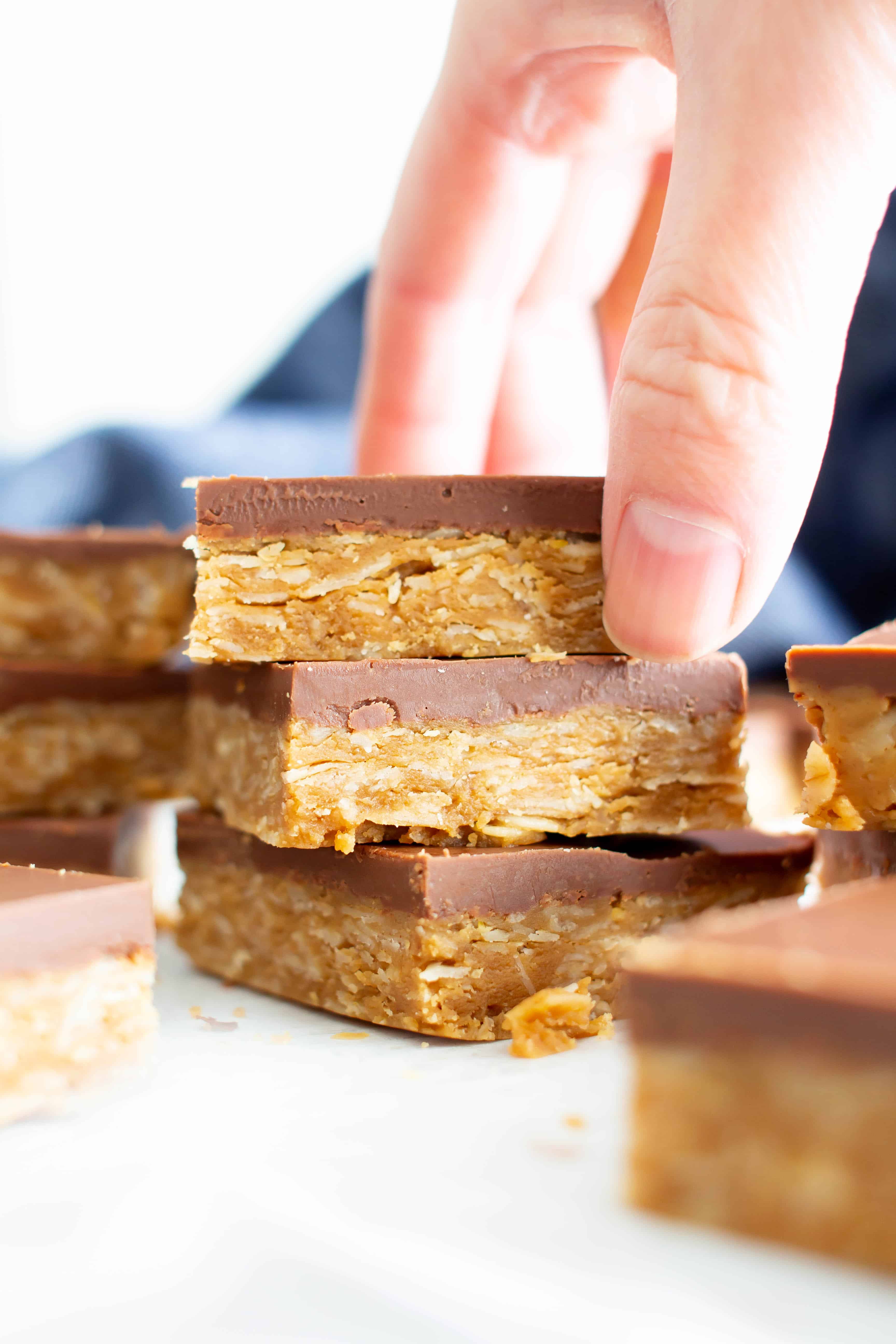 4 Ingredient Healthy No Bake Peanut Butter Cup Oat Bars: this vegan peanut butter oatmeal bars recipe is so easy to make & tastes like peanut butter cups! Chewy peanut butter oatmeal bars with a thick, chocolate topping. #Vegan #GlutenFree #Healthy #PeanutButter #Oats #Oatmeal | Recipe at BeamingBaker.com