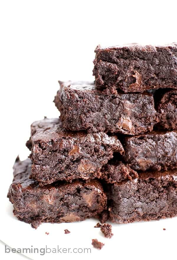 Vegan brownies stacked in a pyramid shape in front of a white background