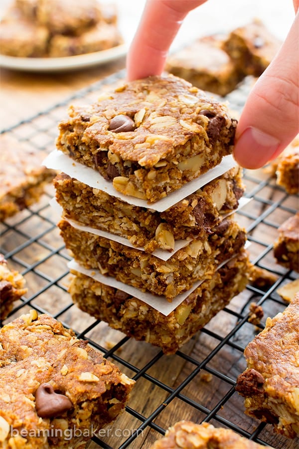 Tall stack of gluten free oat bars with one hand picking up a bar