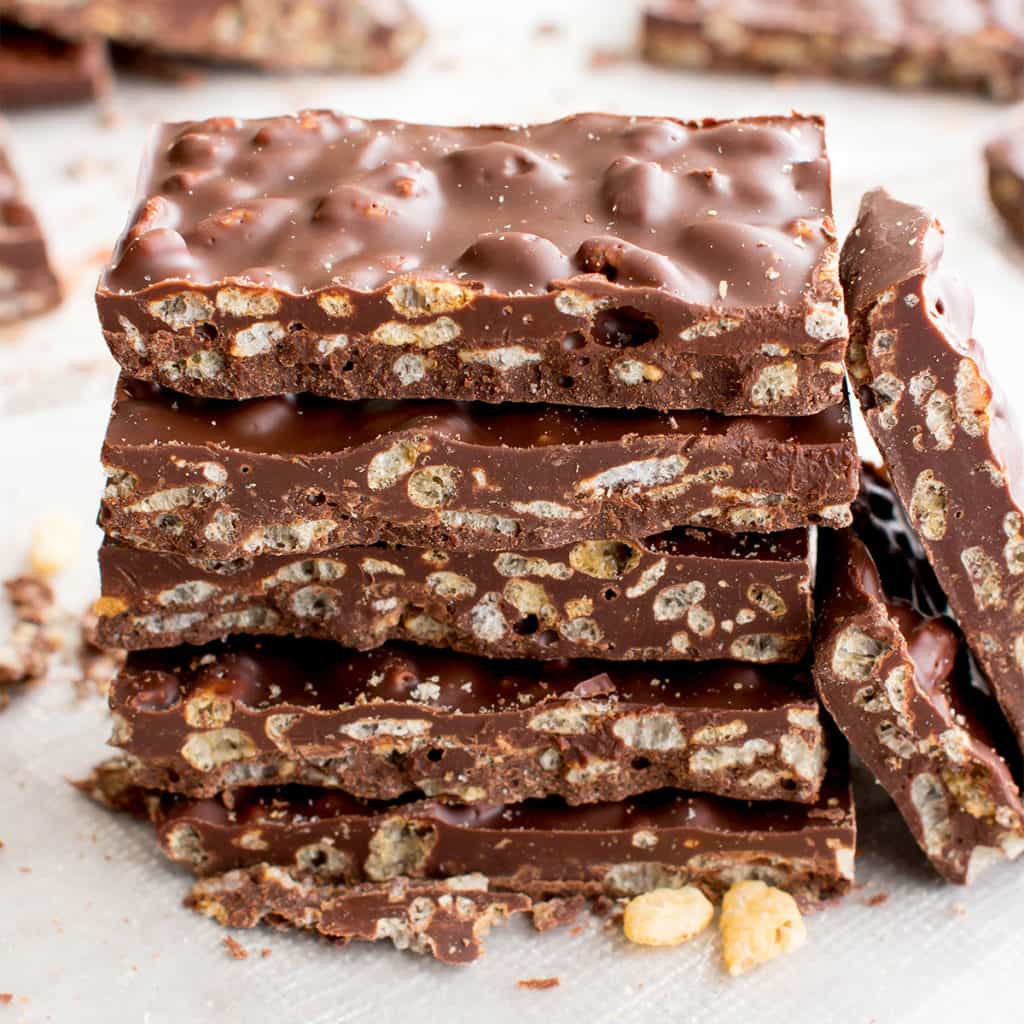 A stack of vegan crunch bars with other placed pieces in the background