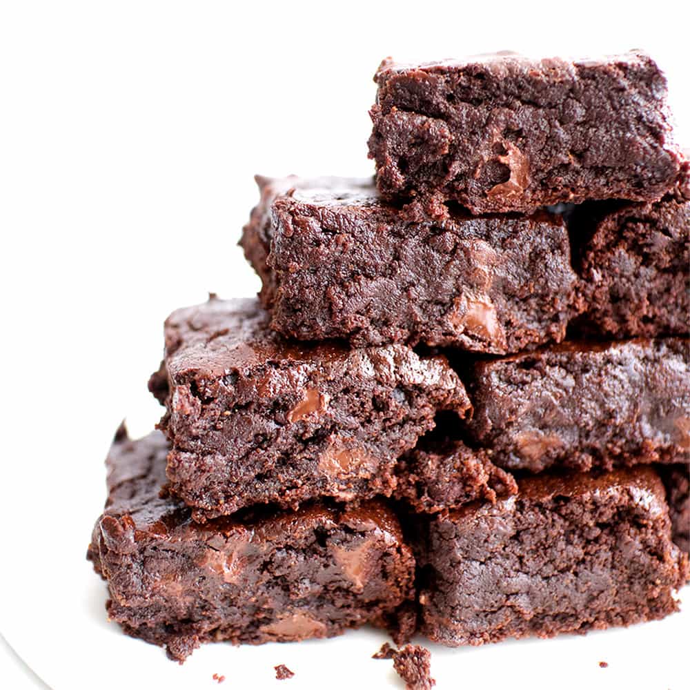fudgy vegan brownies in a stack on white background