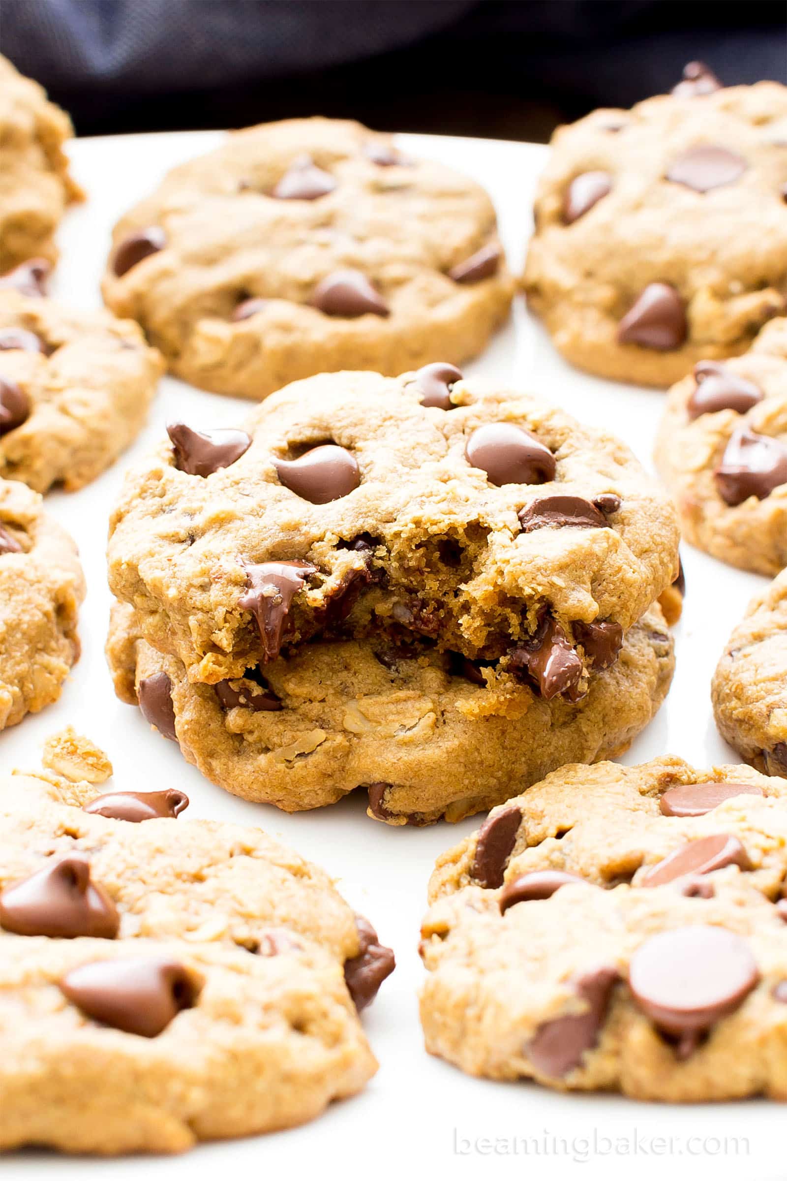 Plate of vegan gluten free chocolate chip cookies with one with a bite taken out of it in the middle