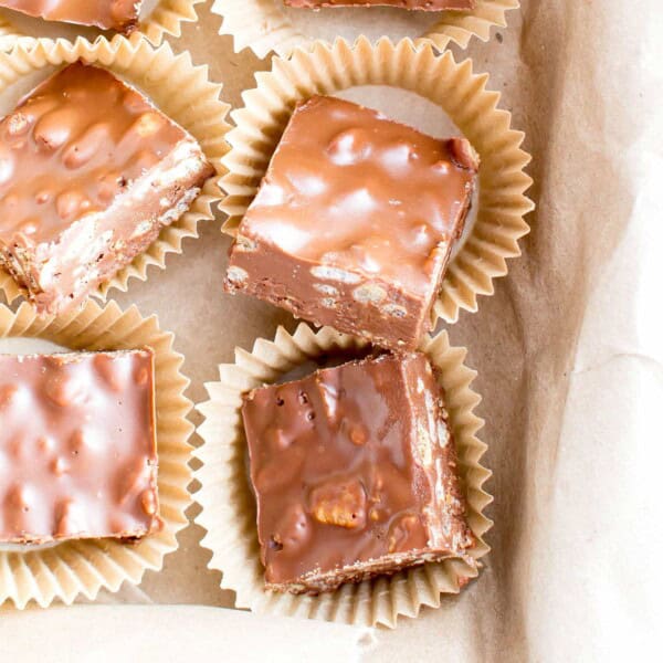 Peanut butter crunch bars cut into squares in brown parchment cups