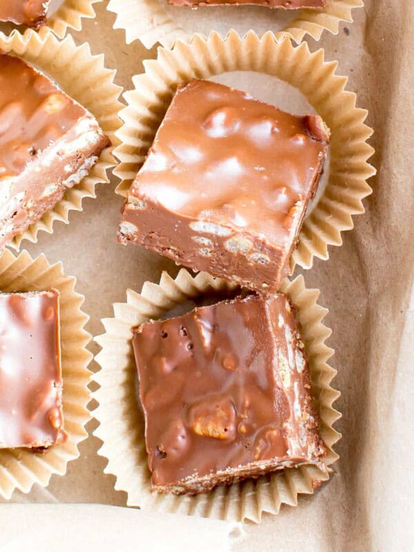 Peanut butter crunch bars cut into squares in brown parchment cups