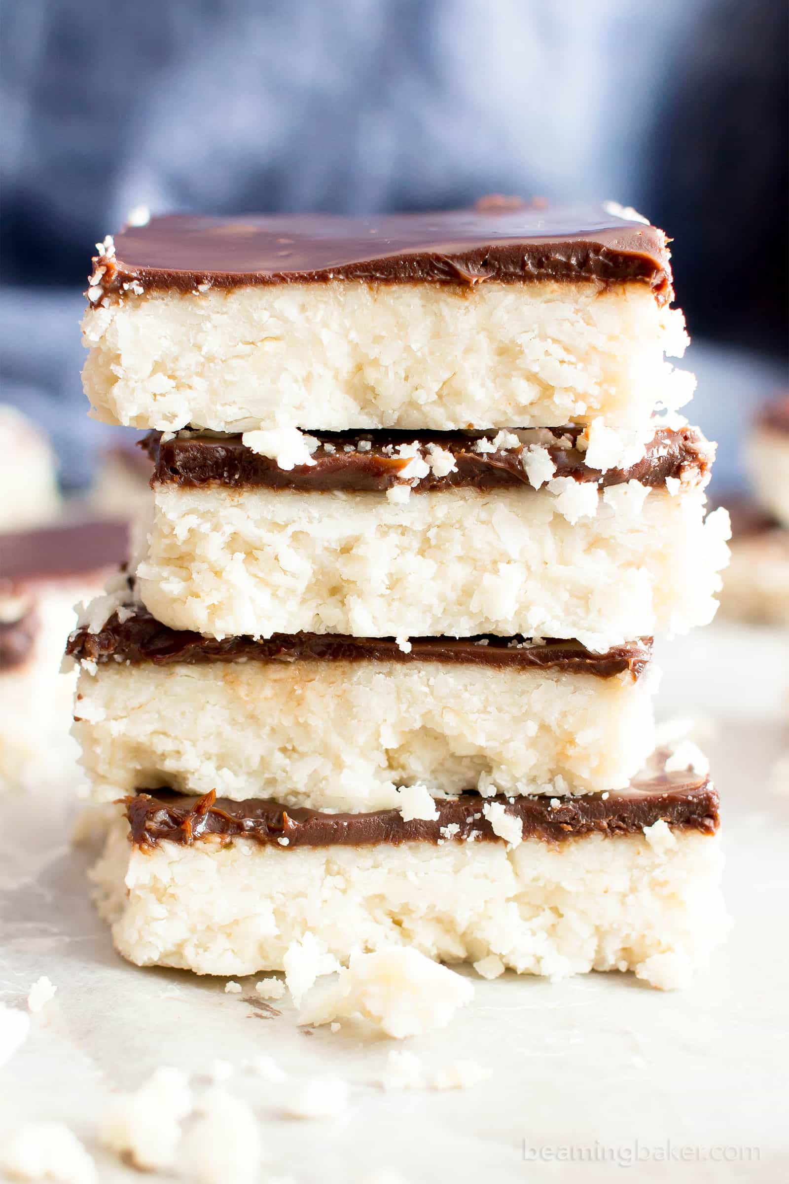 Vegan Coconut Chocolate Bars: this 5 ingredient coconut bars recipe yields thick, indulgent coconut bars enrobed in a velvety layer of rich chocolate. Healthy, Paleo, No Bake, Gluten Free. #Coconut #Bars #Vegan #Chocolate | Recipe at BeamingBaker.com