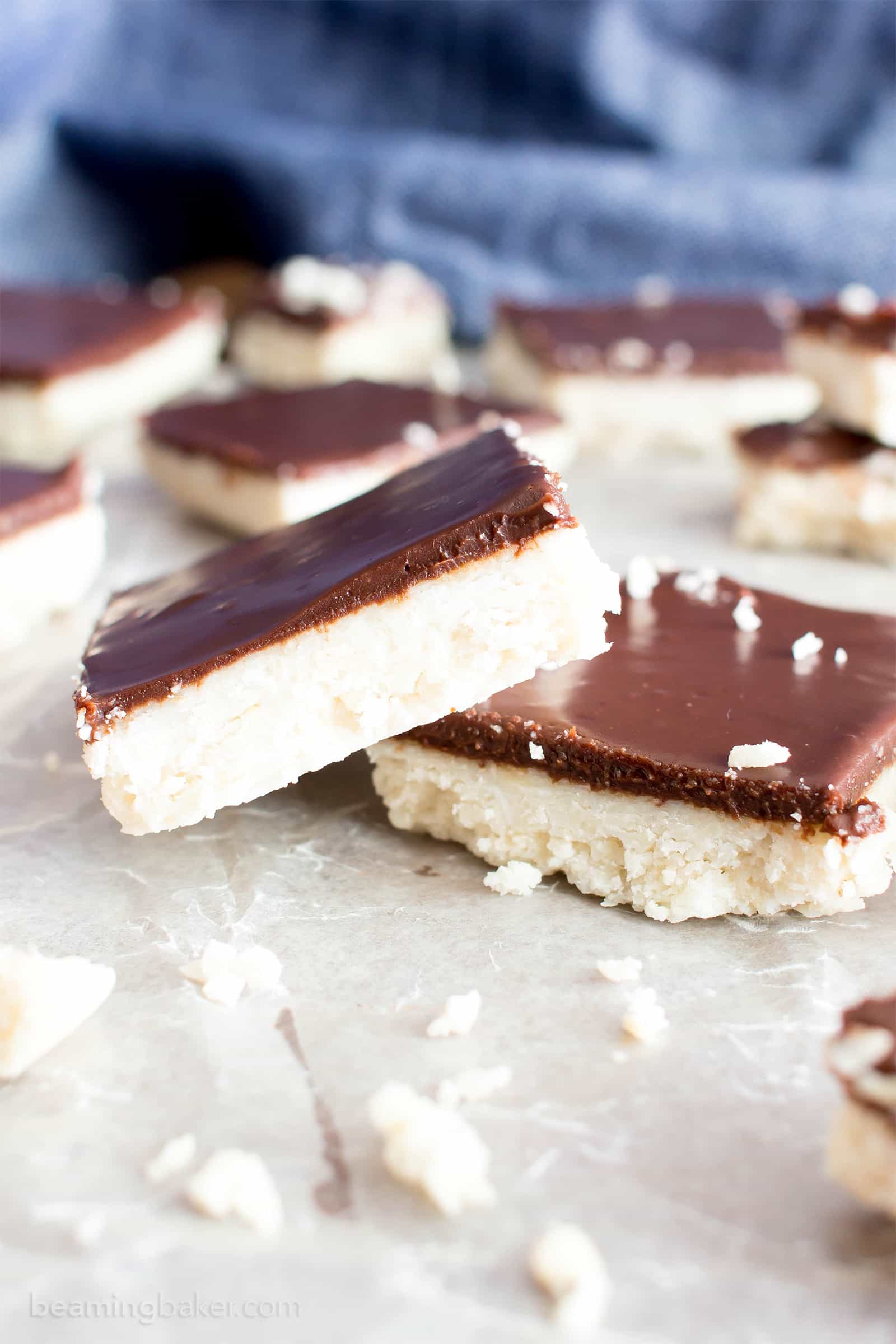 Vegan Coconut Chocolate Bars: this 5 ingredient coconut bars recipe yields thick, indulgent coconut bars enrobed in a velvety layer of rich chocolate. Healthy, Paleo, No Bake, Gluten Free. #Coconut #Bars #Vegan #Chocolate | Recipe at BeamingBaker.com