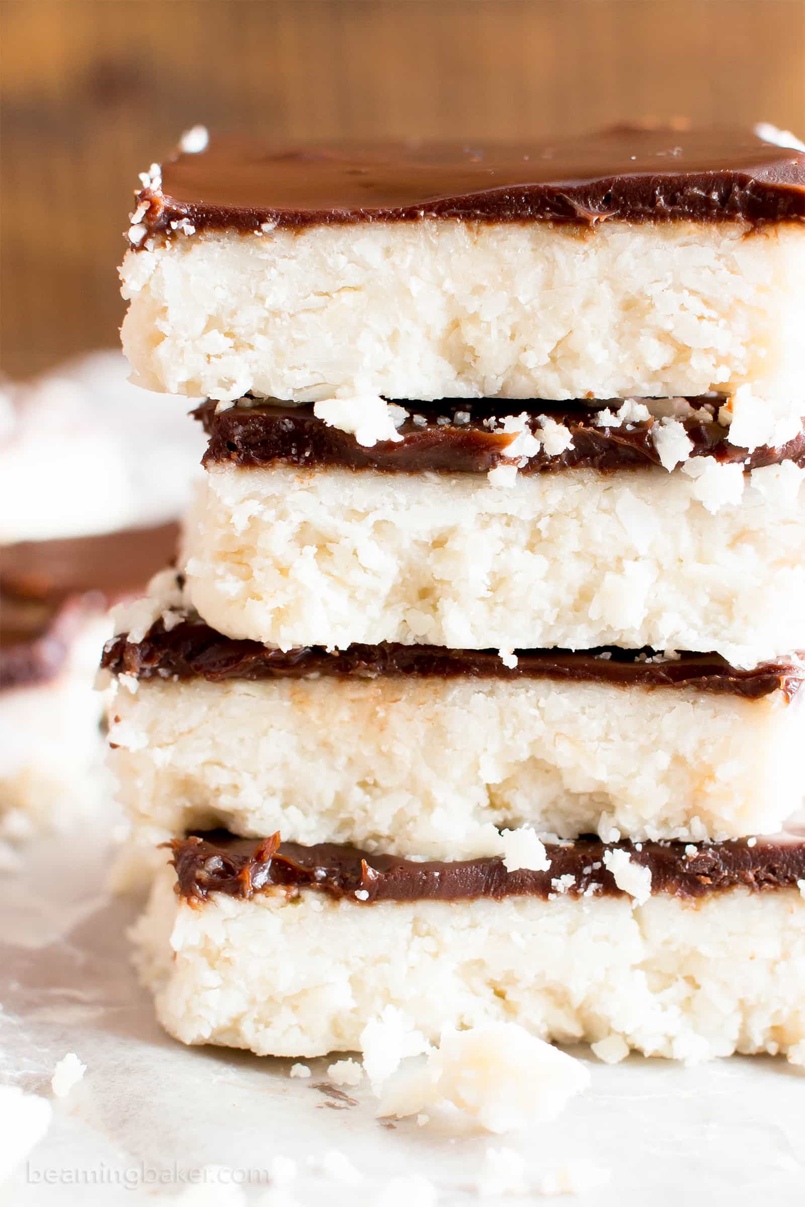 Vegan Coconut Chocolate Bars: this 5 ingredient coconut bars recipe yields thick, indulgent coconut bars enrobed in a velvety layer of rich chocolate. Healthy, Paleo, No Bake, Gluten Free. #Coconut #Bars #Vegan #Chocolate | Recipe at BeamingBaker.com