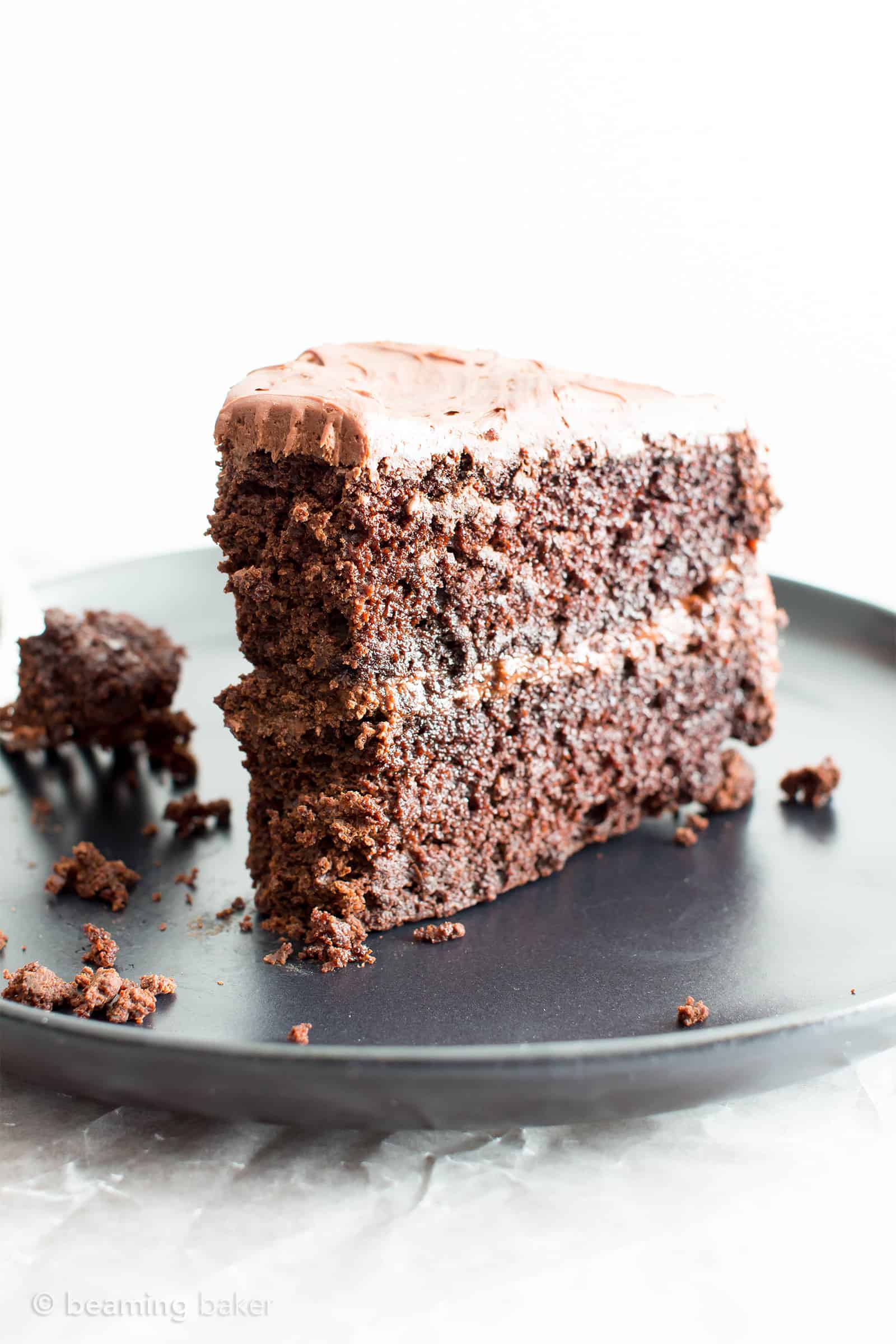 Slice of vegan gluten free chocolate cake on a black plate with a bite taken out of it