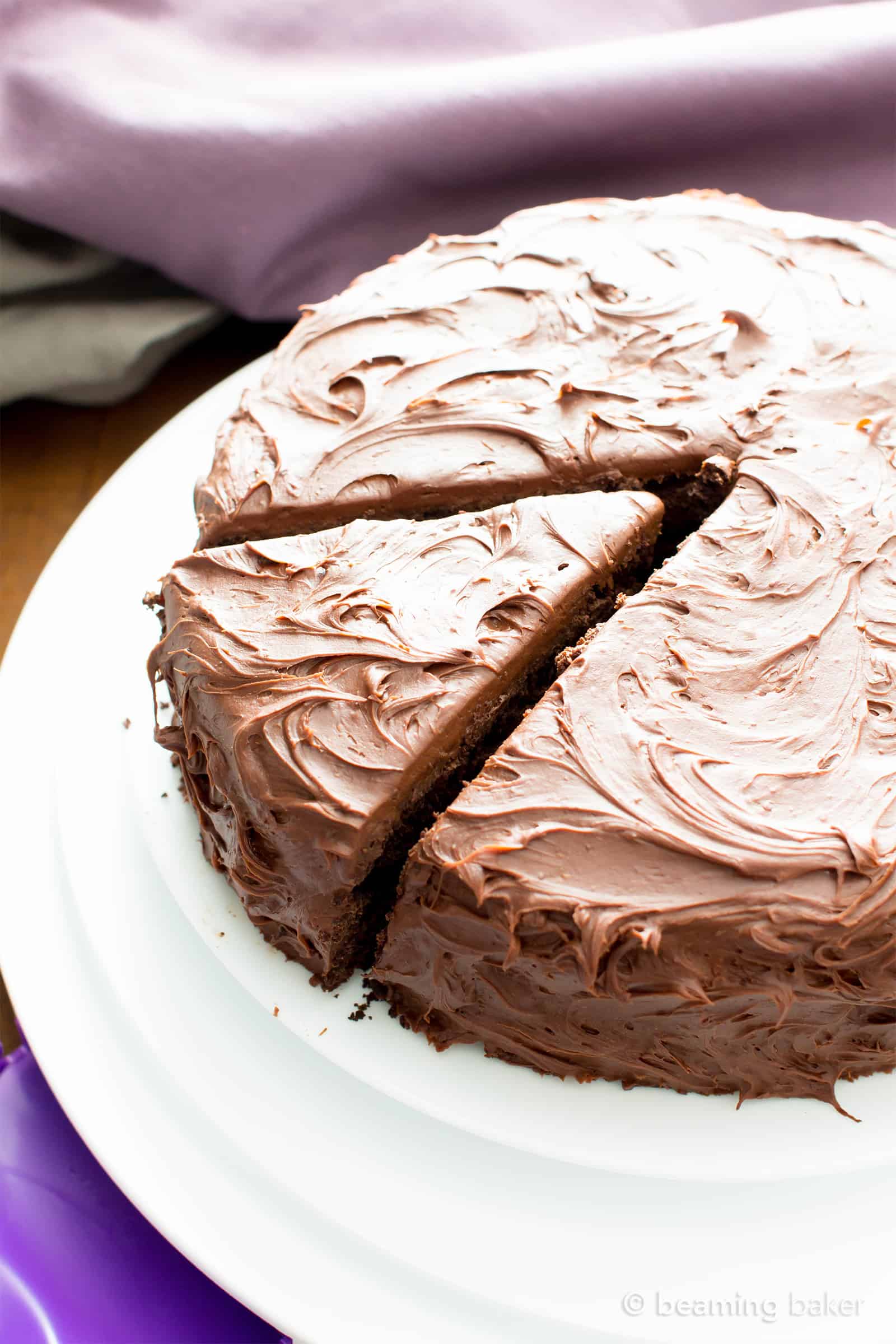 Oat flour chocolate cake on a white plate, with a slice cut out ready to be served