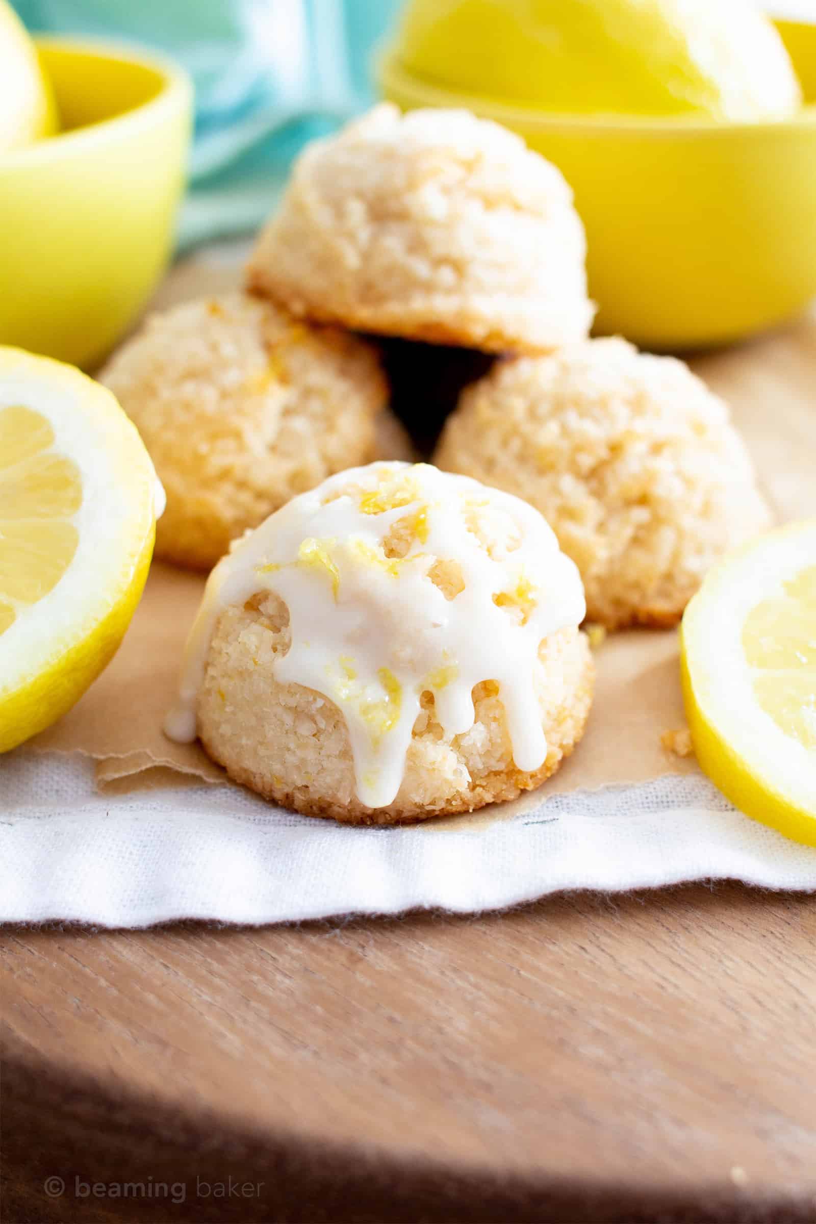 A glazed macaroons on a table with lemons and unglazed macaroons behind it.