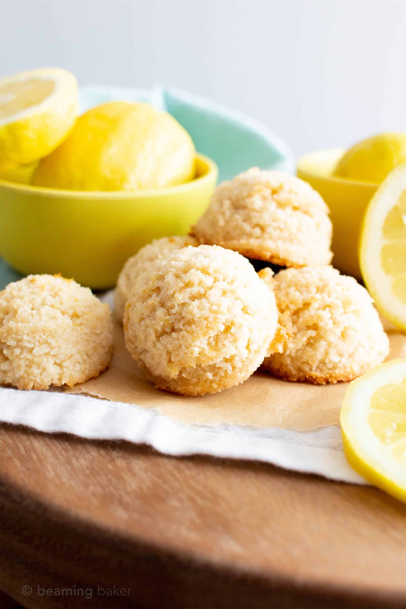 Batch of lemon coconut macaroons with lemons around them.