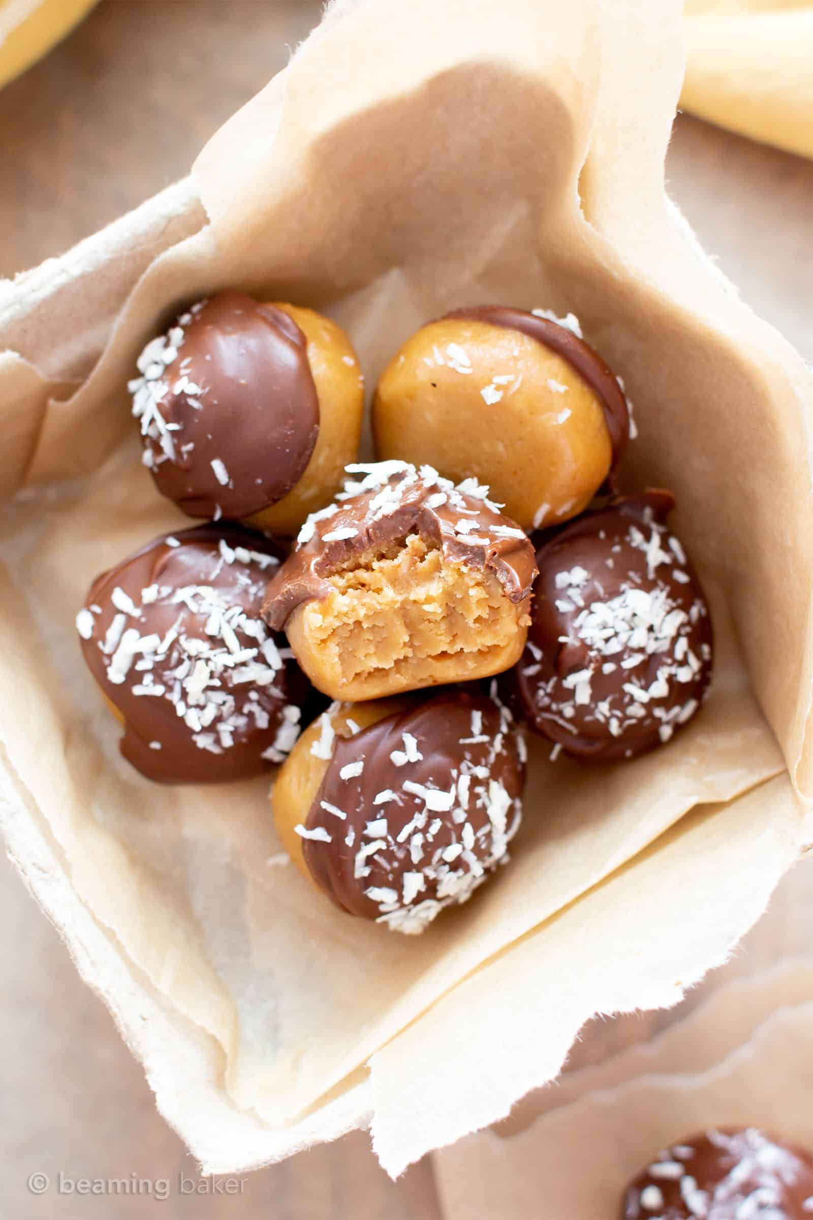 5 Ingredient Vegan Peanut Butter Coconut Truffles (V, GF): an easy recipe for decadent peanut butter coconut truffles enrobed in a thick layer of chocolate, and topped with coconut flakes. Made with healthy ingredients. #PeanutButter #HealthyDesserts #ChristmasCandy #VeganChristmas #GlutenFreeVegan #BeamingBaker #Coconut #CandyRecipe | Recipe at BeamingBaker.com