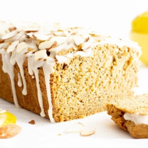 Loaf of lemon bread with end sliced off, with almonds and lemon glaze on top.