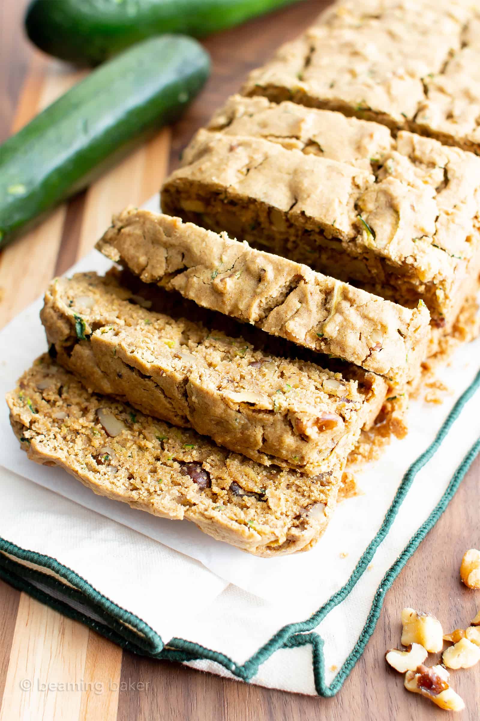 Sliced gluten free zucchini bread served on a wooden platter with fresh  zucchini