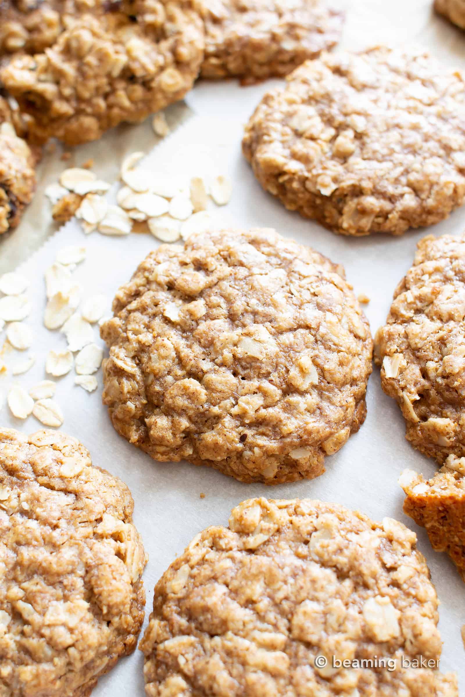 close up of vegan oatmeal cookies on parchment paper with rolled oats