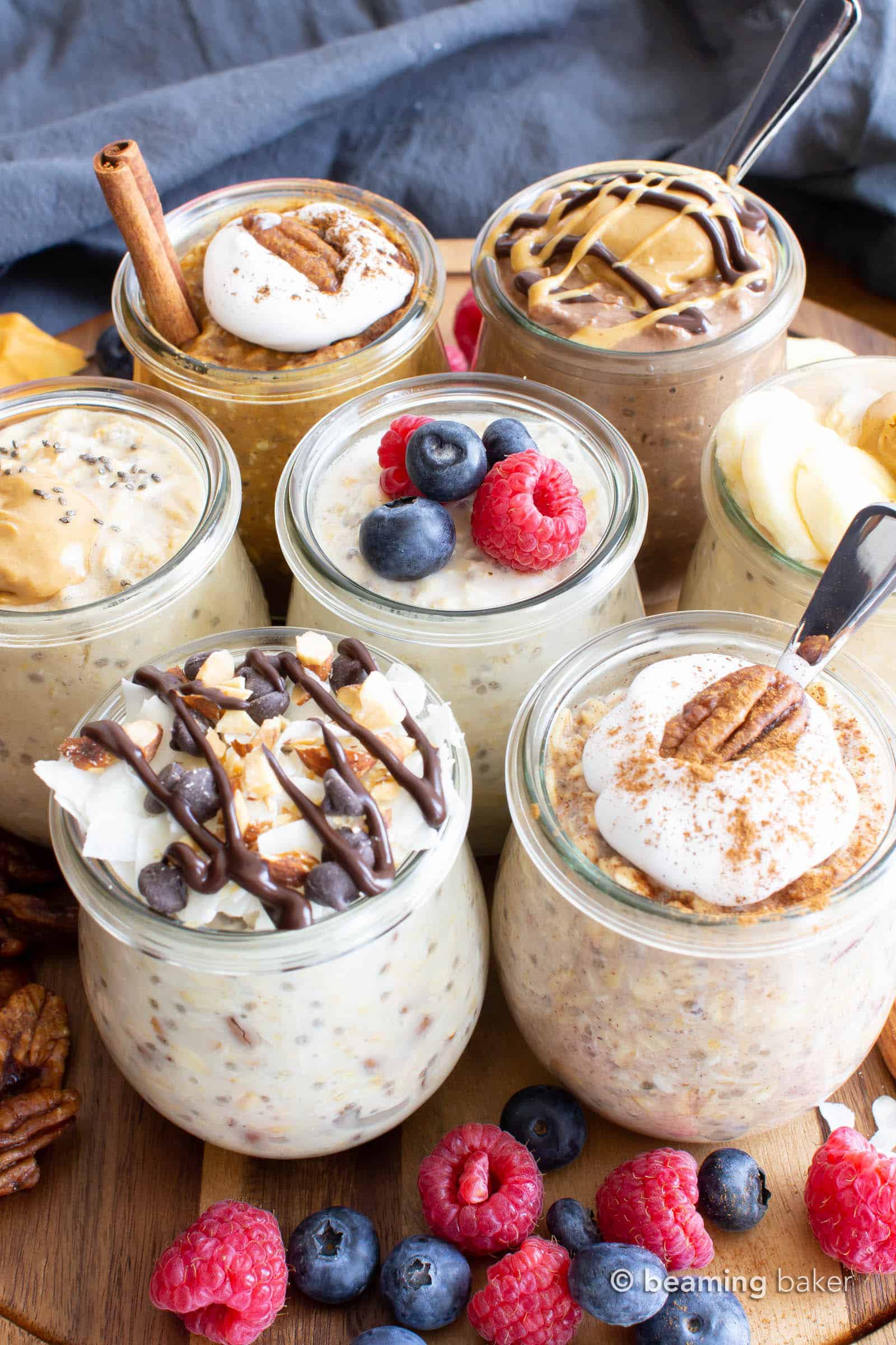 A buffet of overnight oats made vegan with many flavor variations in overnight oats jars with spoons and toppings