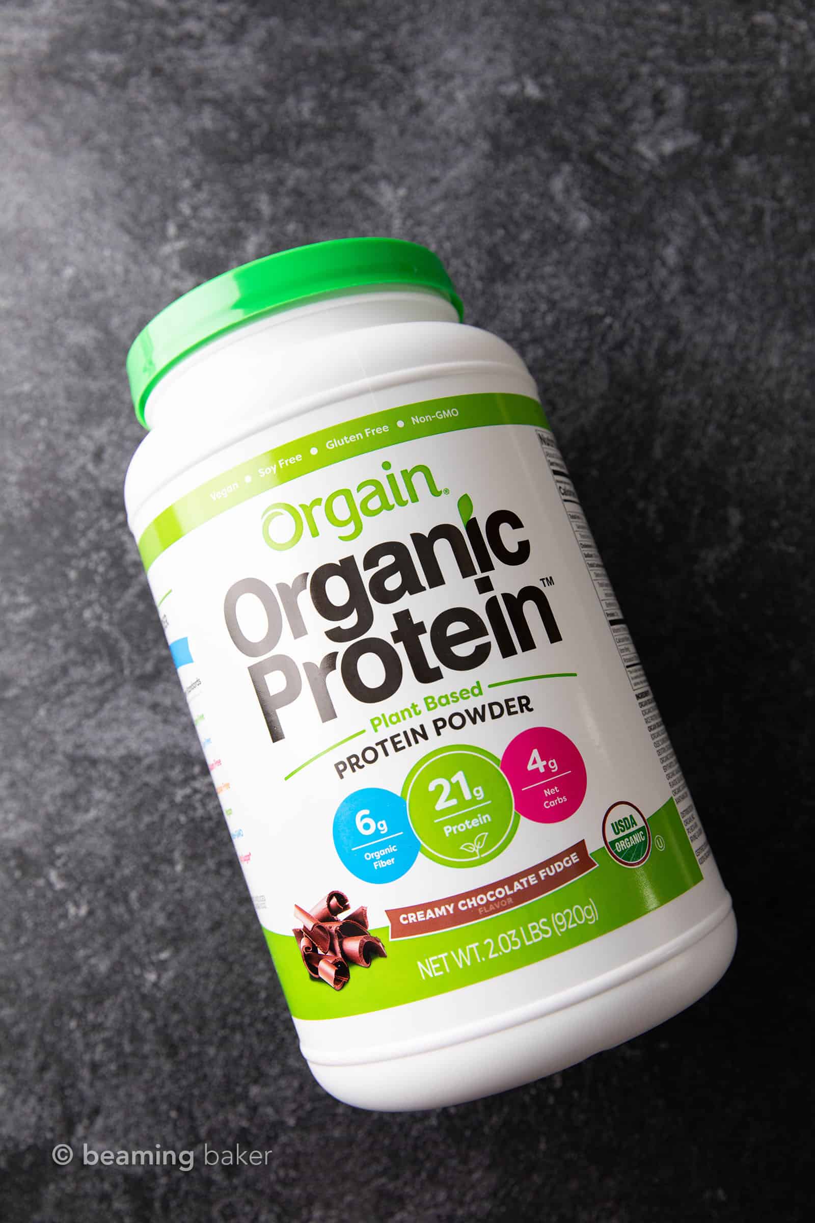 Container of Orgain vegan chocolate protein powder on grey background