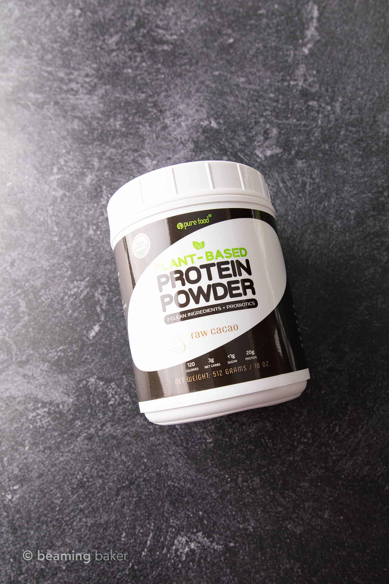 Container of Pure Food vegan chocolate protein powder on grey background