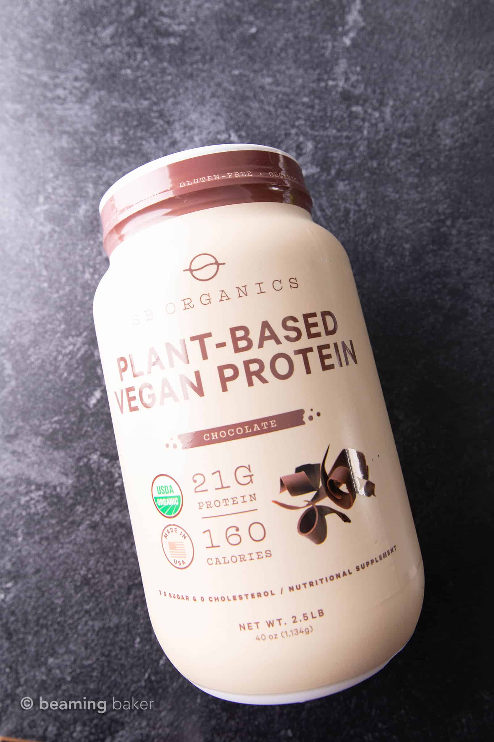 Container of SB Organics vegan chocolate protein powder on grey background