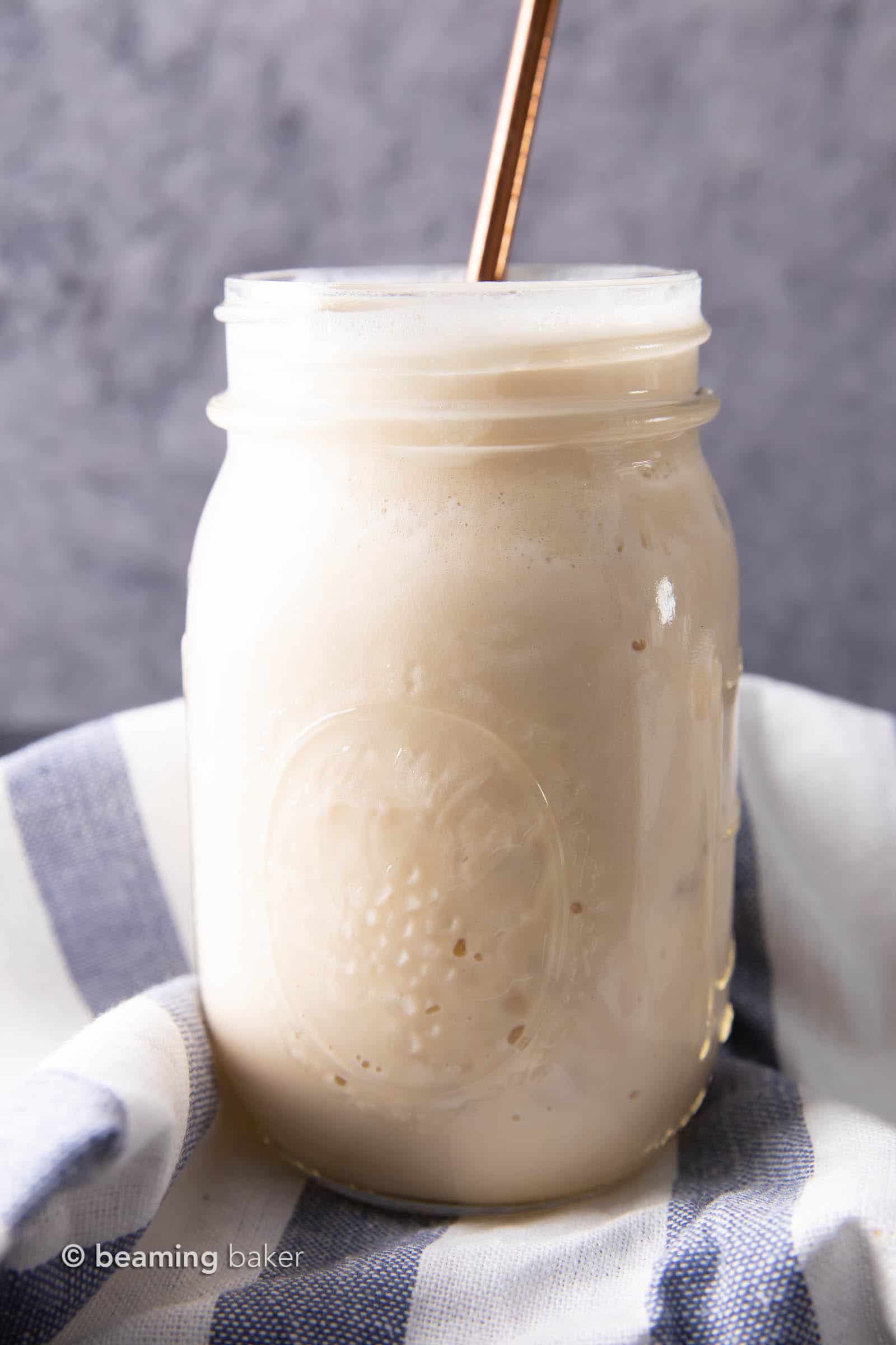 Closeup picture of vegan protein shake in mason jar with straw on top