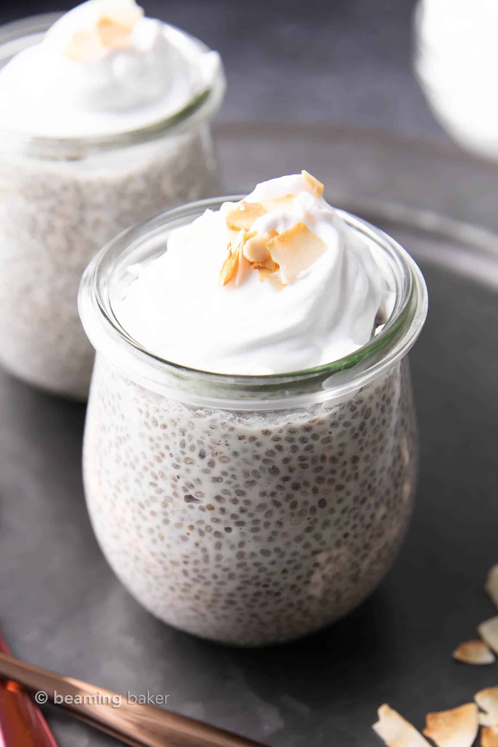 Two jars of vegan gluten free coconut chia pudding with coconut whip and coconut pieces on top