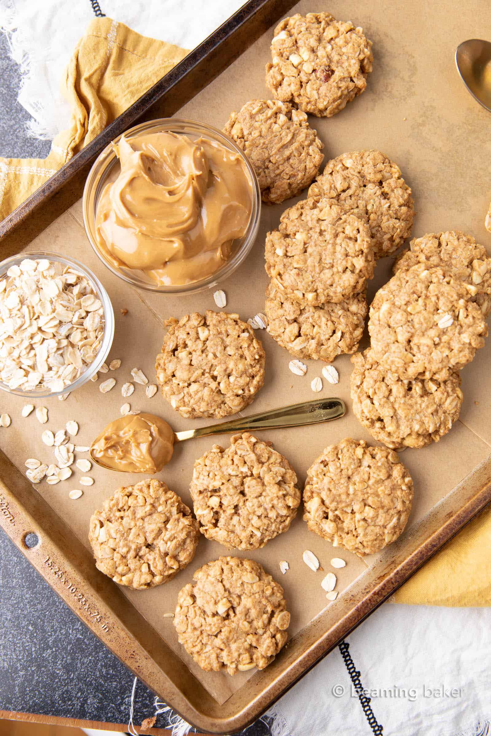 Fresh-baked healthy peanut butter oatmeal cookies on a baking sheet with a bowl of peanut butter and oats