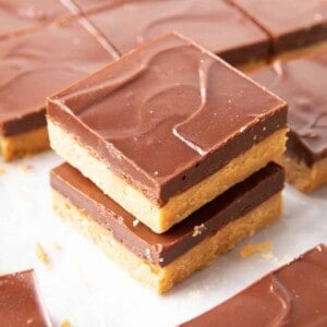 Keto Peanut Butter Bars: only 4 ingredients for soft ‘n dense no bake peanut butter bars topped with a thick layer of chocolate peanut butter. Sink your teeth into the best keto peanut butter chocolate bars! Like PB cups in bar form. #Keto #PeanutButter #LowCarb #Ketogenic #Chocolate | Recipe at BeamingBaker.com