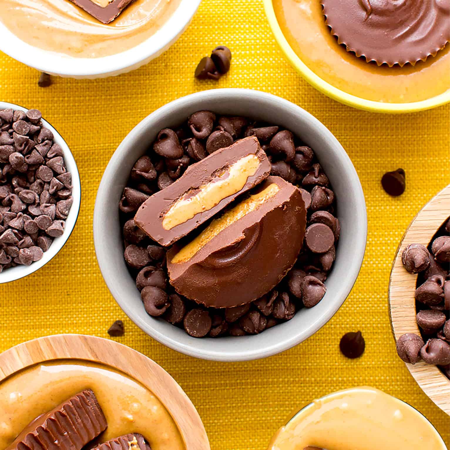 A vegan peanut butter cup split in half sitting in a bowl of chocolate chips