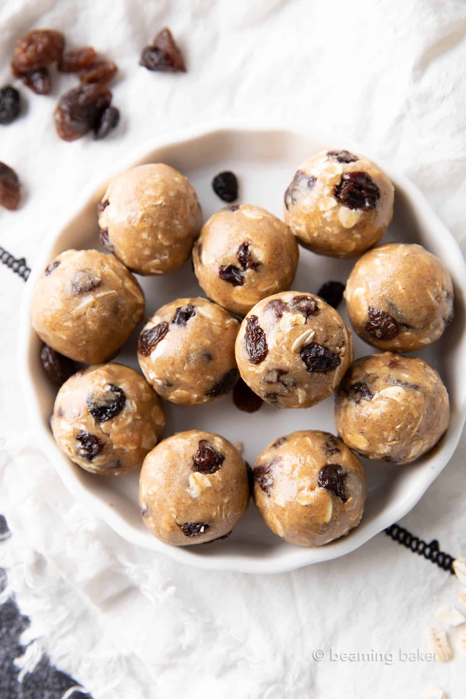 medium close stack of oatmeal raisin energy bites on a plate with oats and raisins