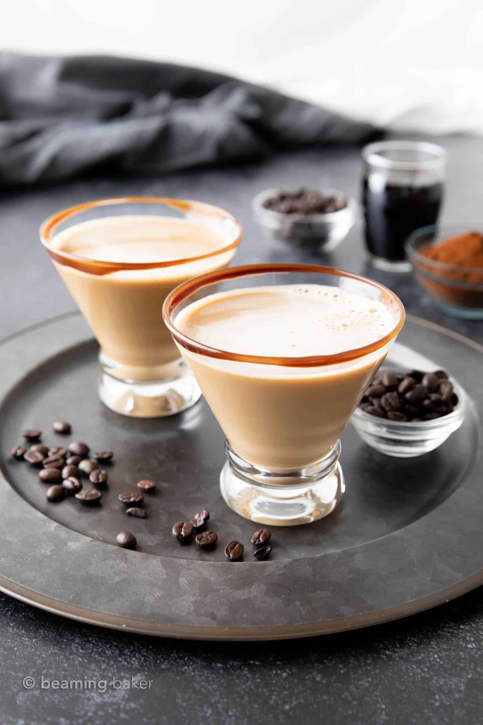 Two chocolate espresso martinis served on a plate with coffee beans