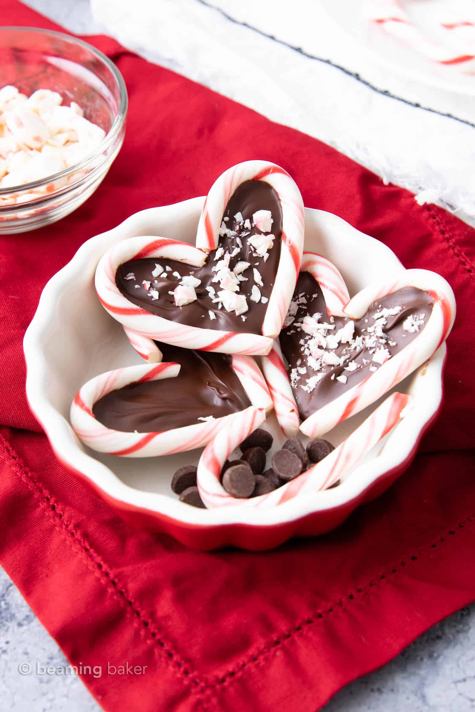 Closeup of chocolate heart candy canes in a white bowl on red cloth
