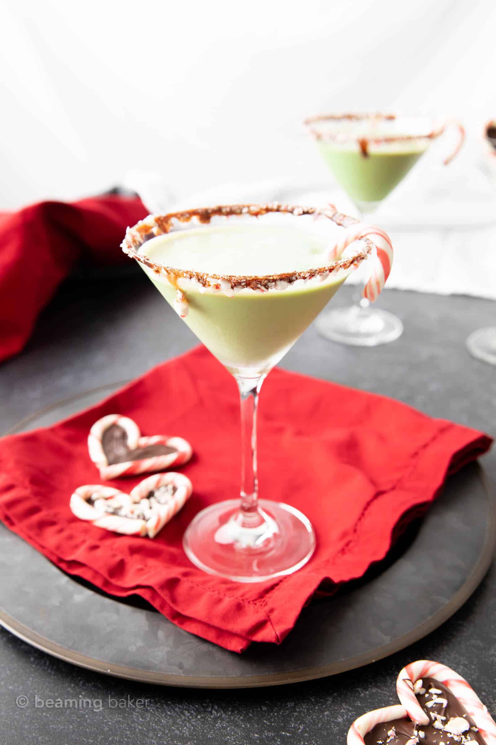 Chocolate mint martini on a red cloth with candy cane hearts and another martini in the background