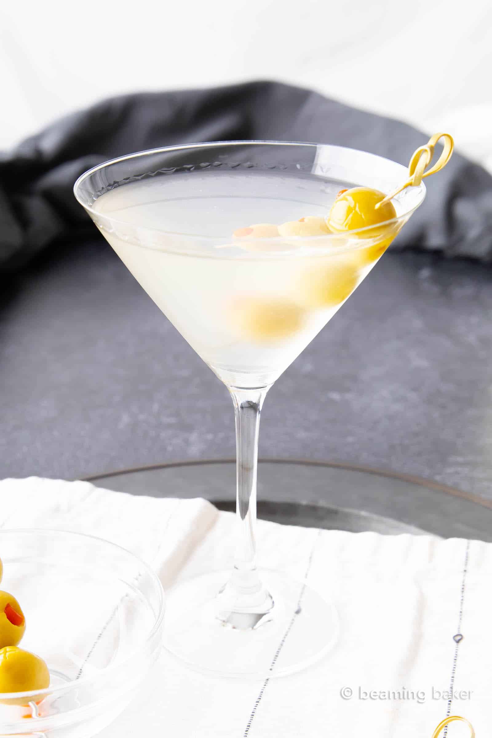 A large martini glass filled with dirty martini cocktail on a white napkin