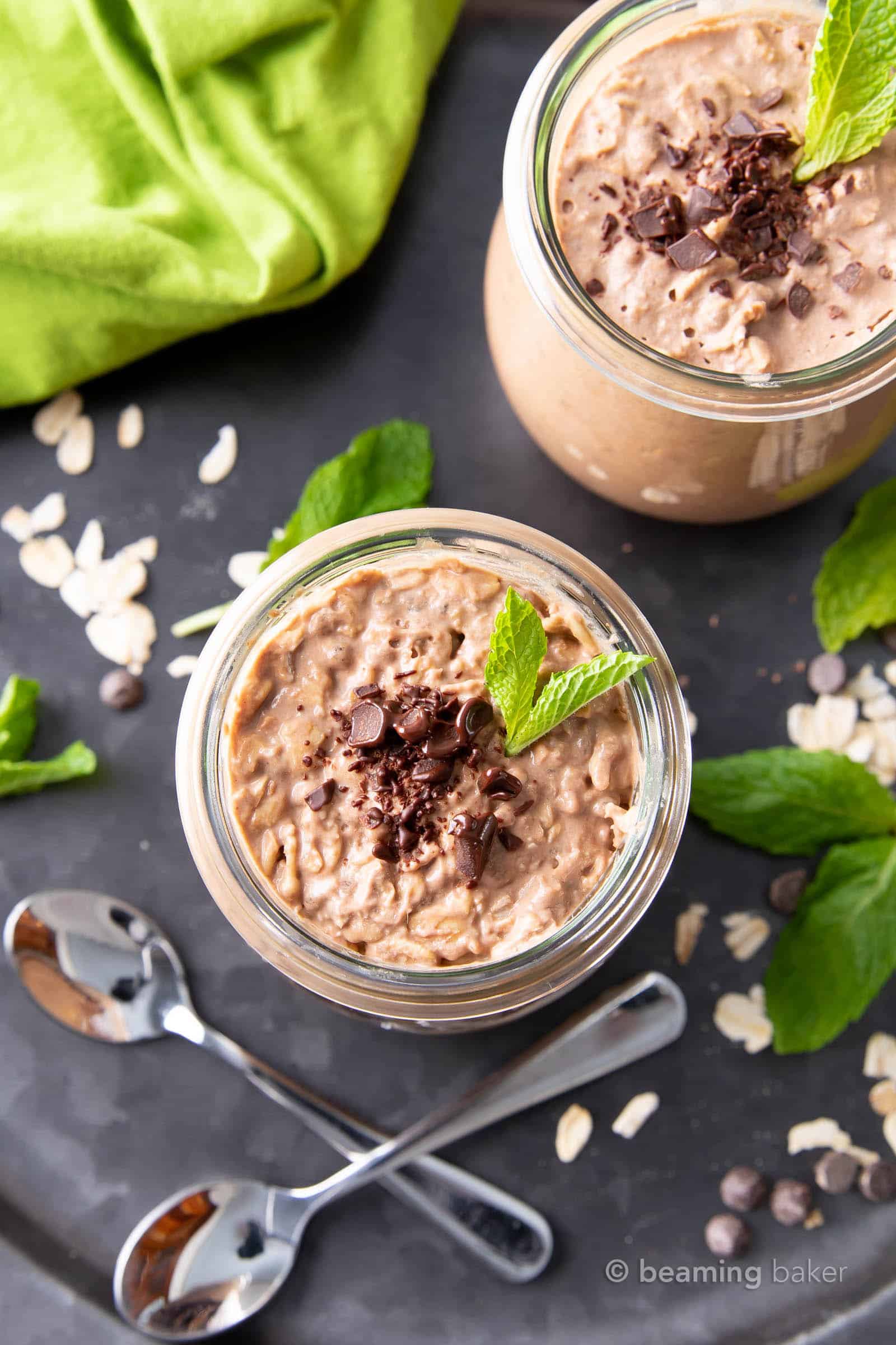 closeup of two jars of mint chocolate chip overnight oats with melted chocolate chips on top and mint garnish
