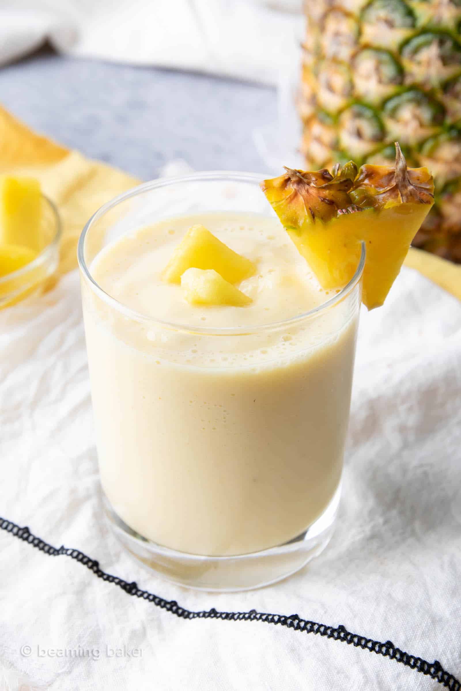 closeup view of how to make a pineapple smoothie with milk in a glass with a pineapple wedge
