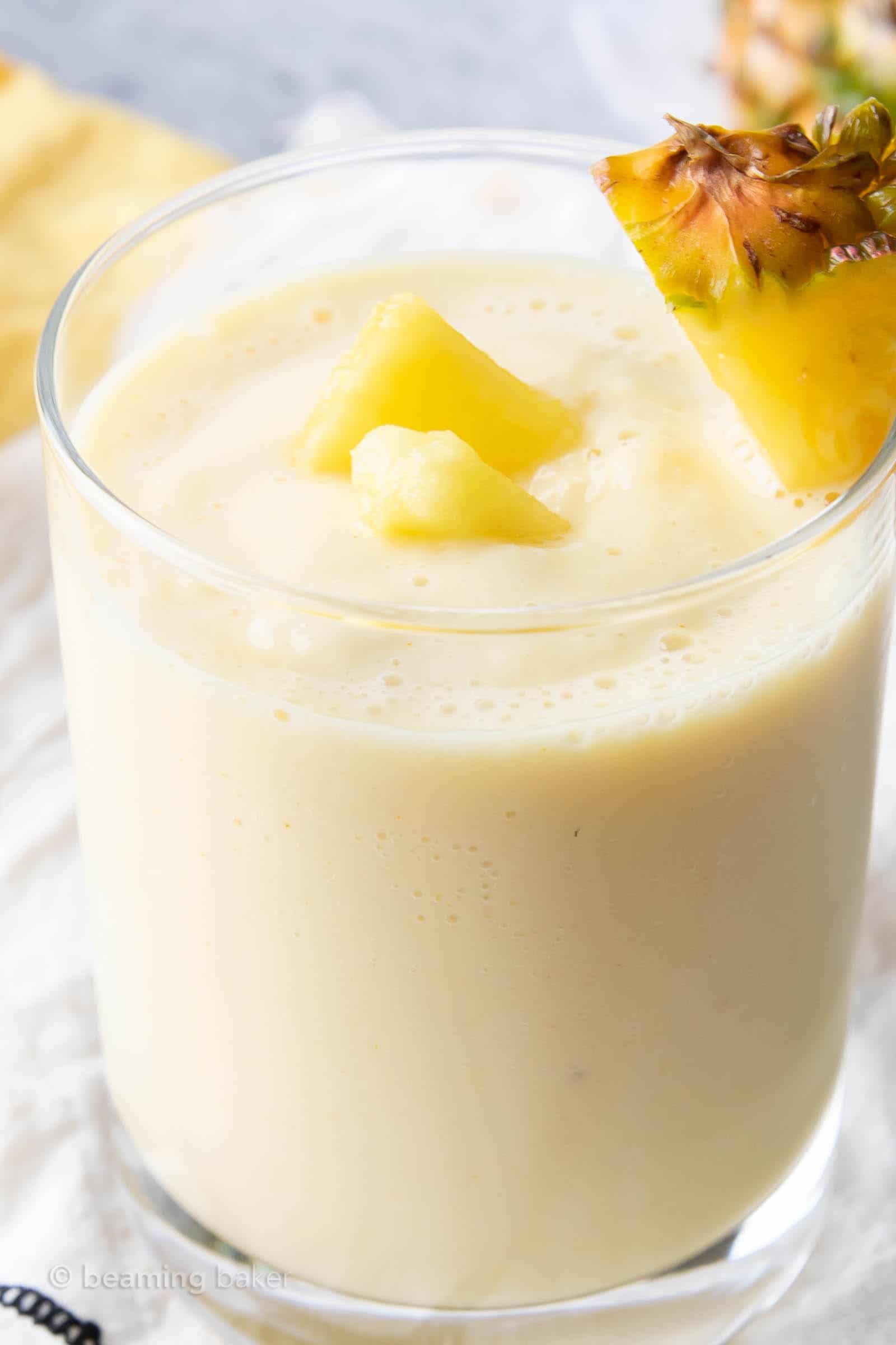 super closeup of how to make a pineapple smoothie with yogurt served in a glass with pineapple pieces as garnish