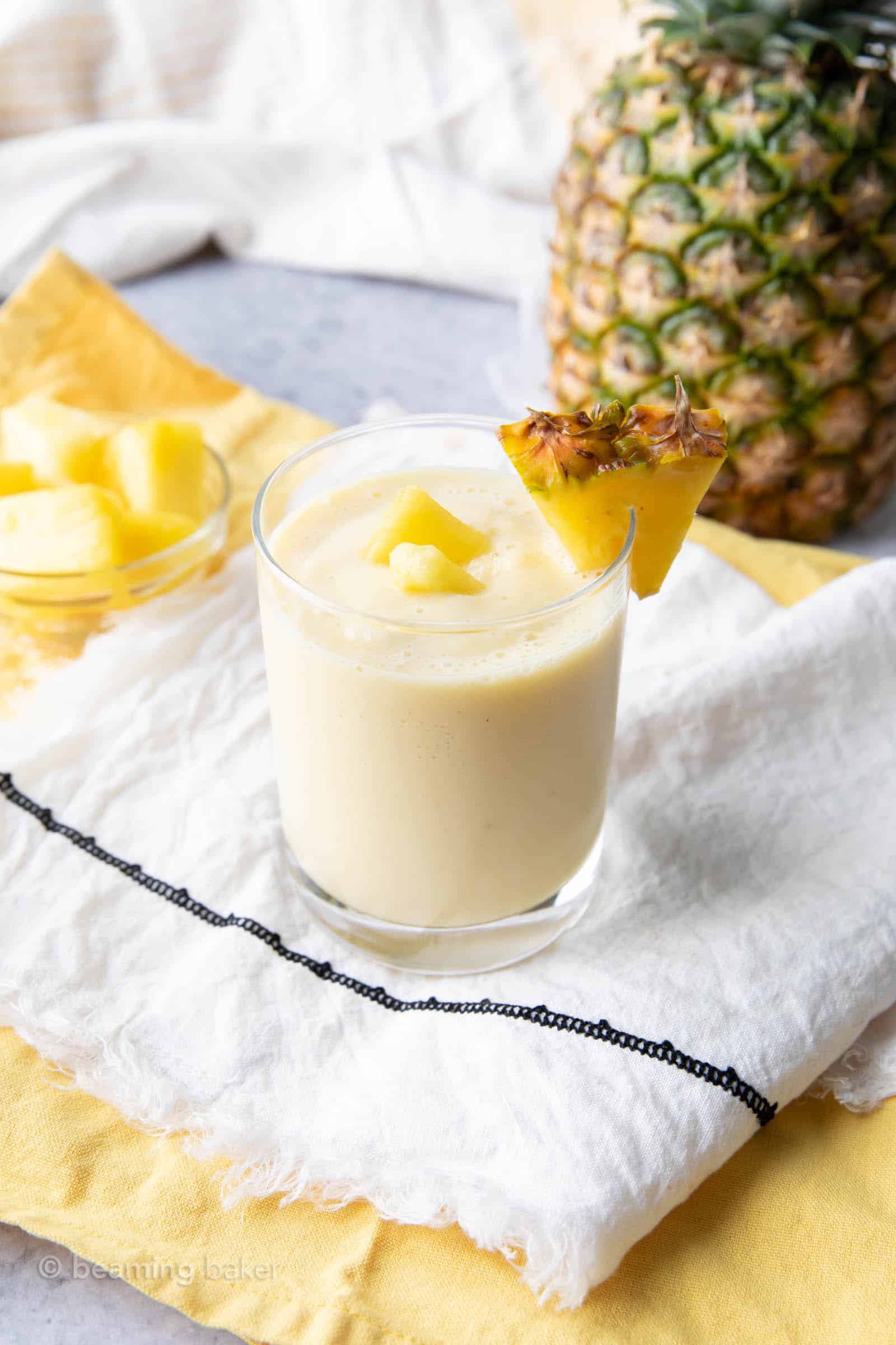 the best pineapple smoothie on a white and yellow cloth with a both of pineapple chunks