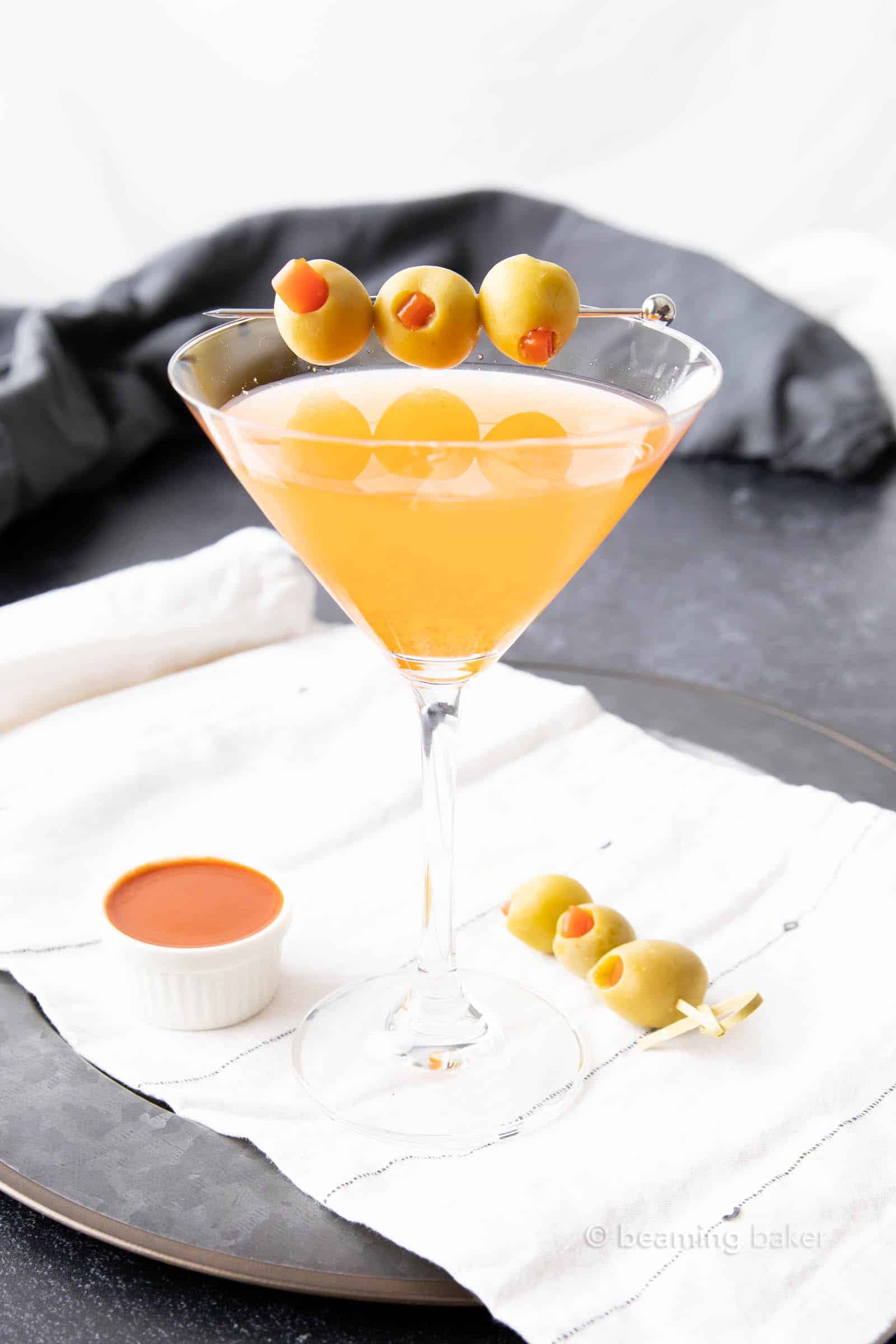 spicy dirty martini with olive skewer on a napkin