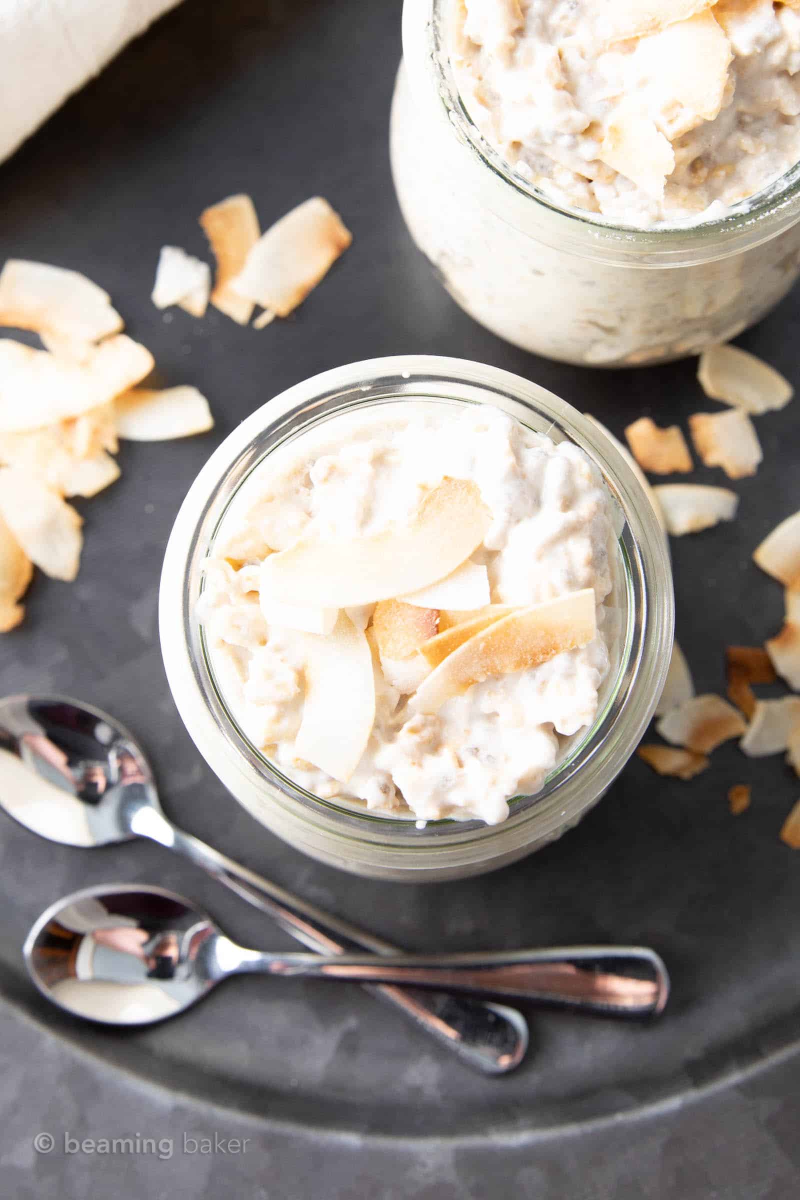 closeup overhead view of two jars of coconut overnight oats with two spoons and a matching